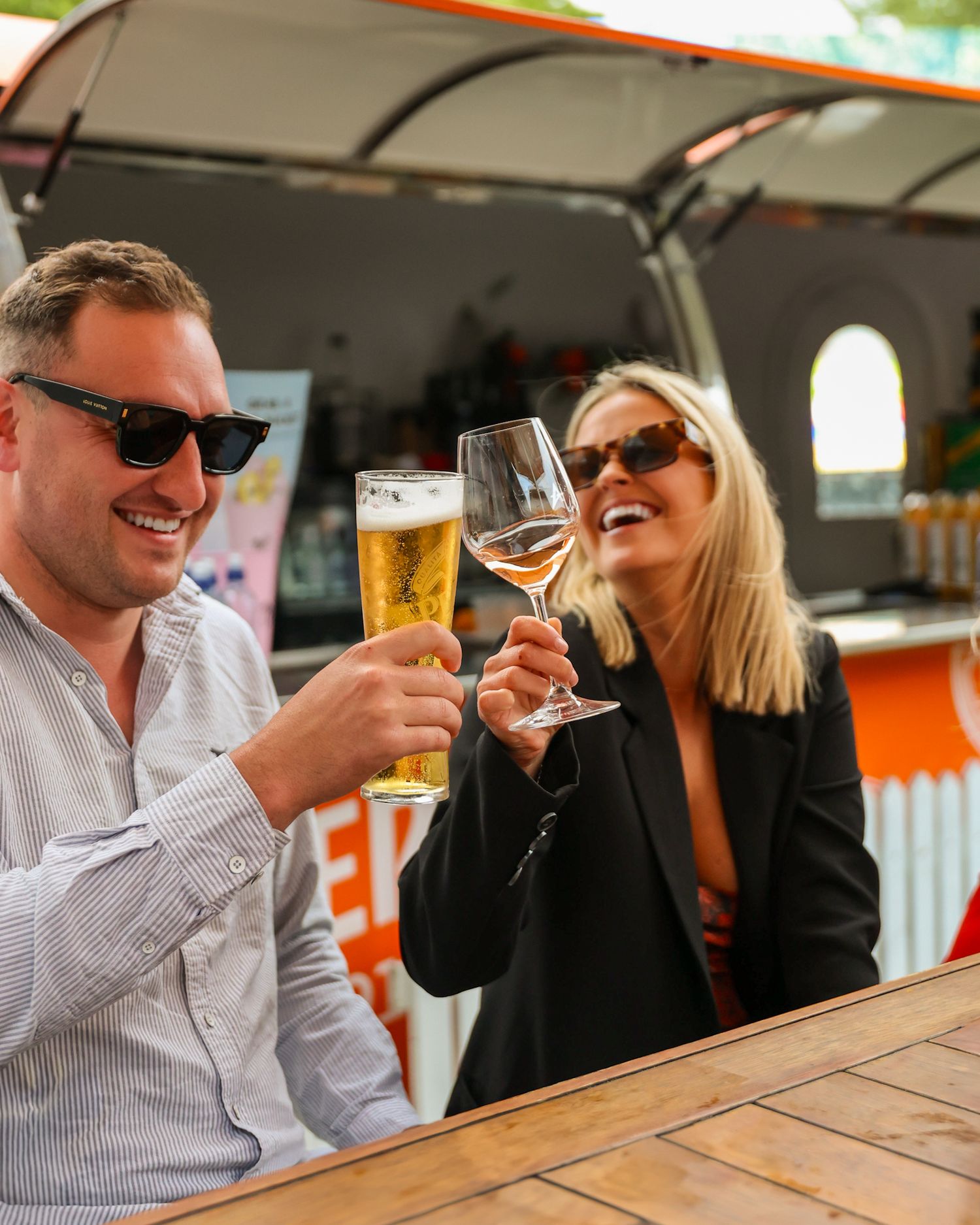 Two people cheersing a pint of Heineken and a glass of wine at a bar.