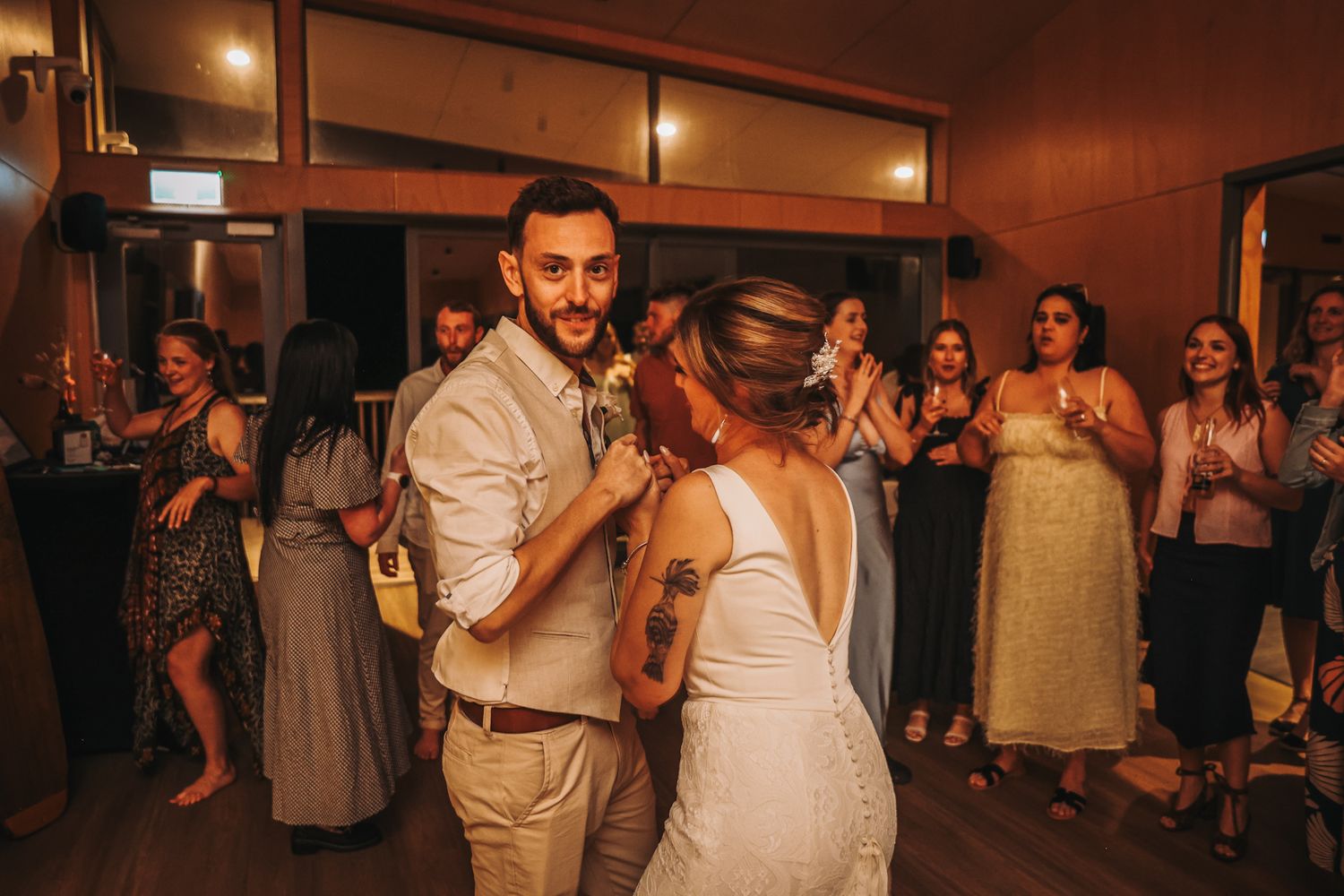 Newly married couple on the dance floor at their wedding. Groom catches the camera and smiles.