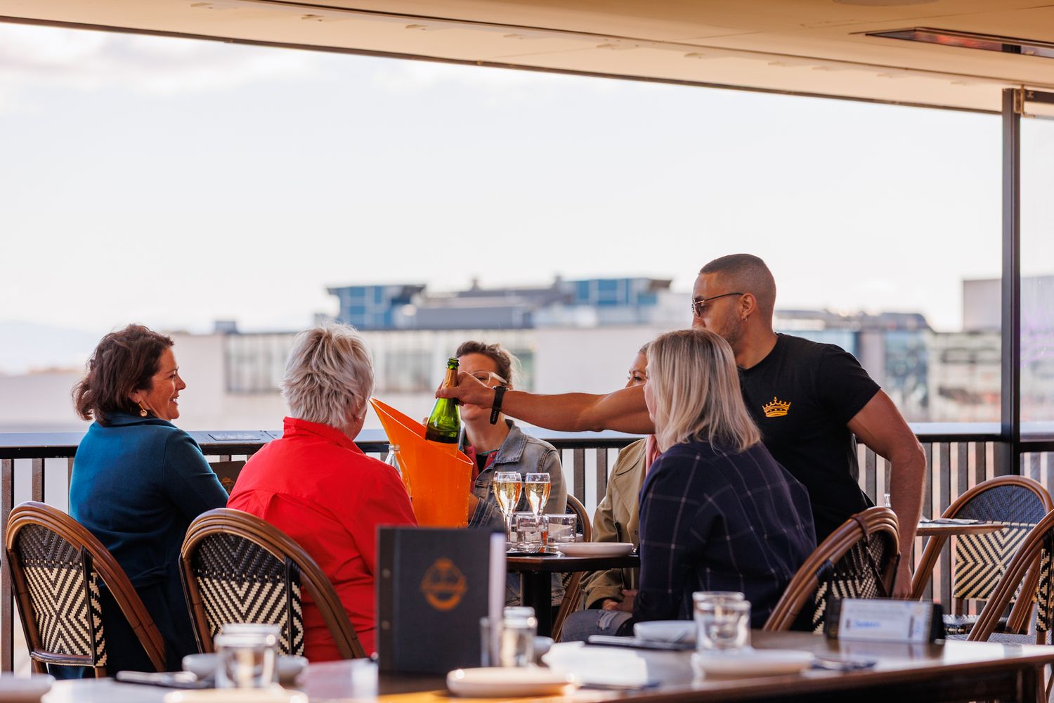 Waiter serving a bottle of Veuve Clicquot Champagne to a group of ladies dining at Mr. Brightsid Rooftop Bar