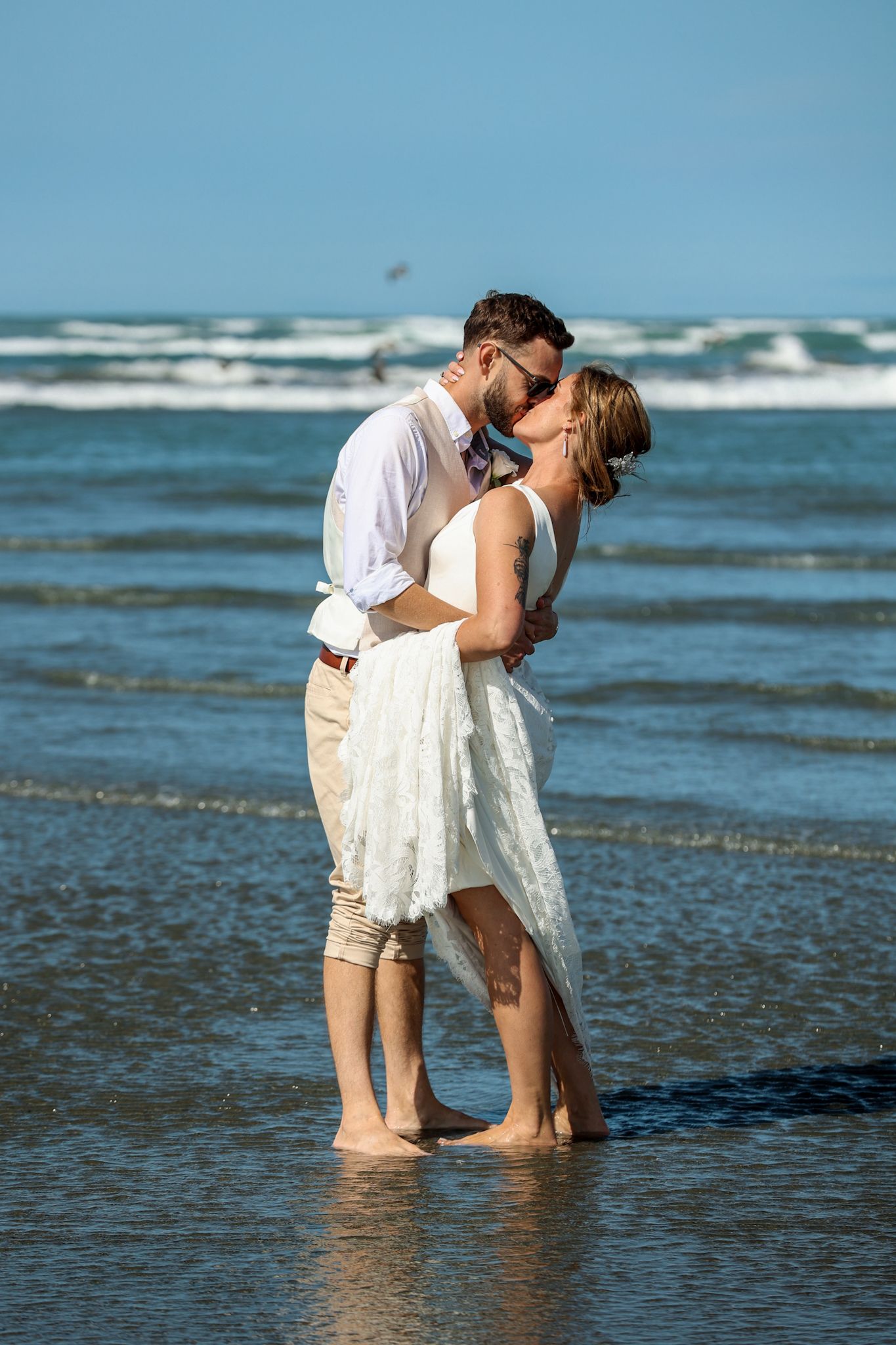 Newlyweds during their portrait photography session in the surf at Southshore Beach, Christchurch.