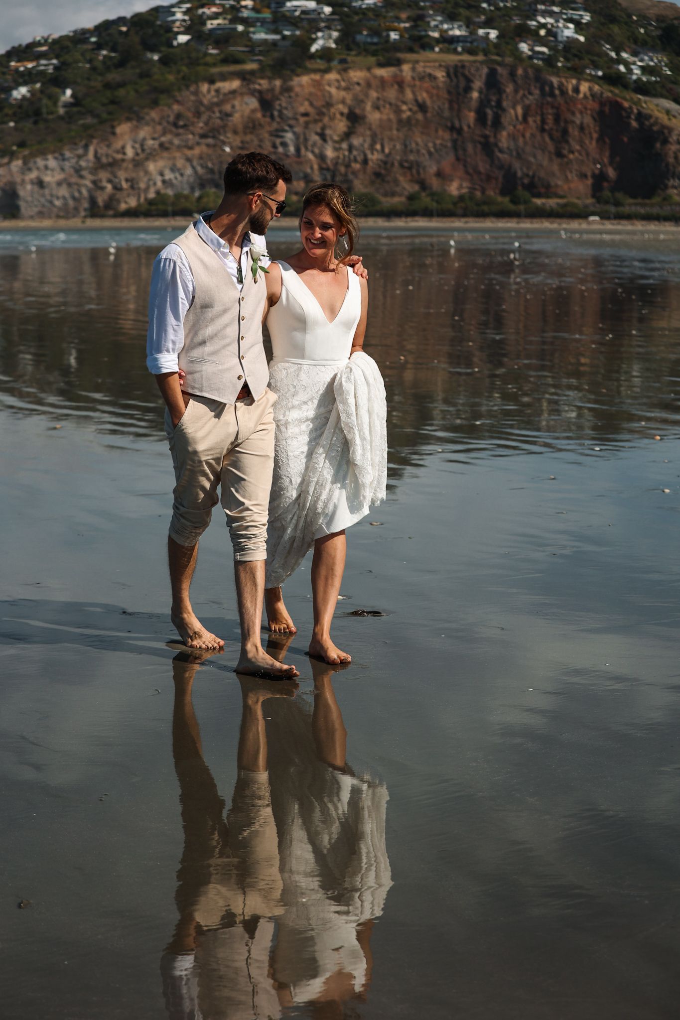 Bride and groom walking barefoot in the surf at Southshore New Brighton Beach during their newlywed portraits