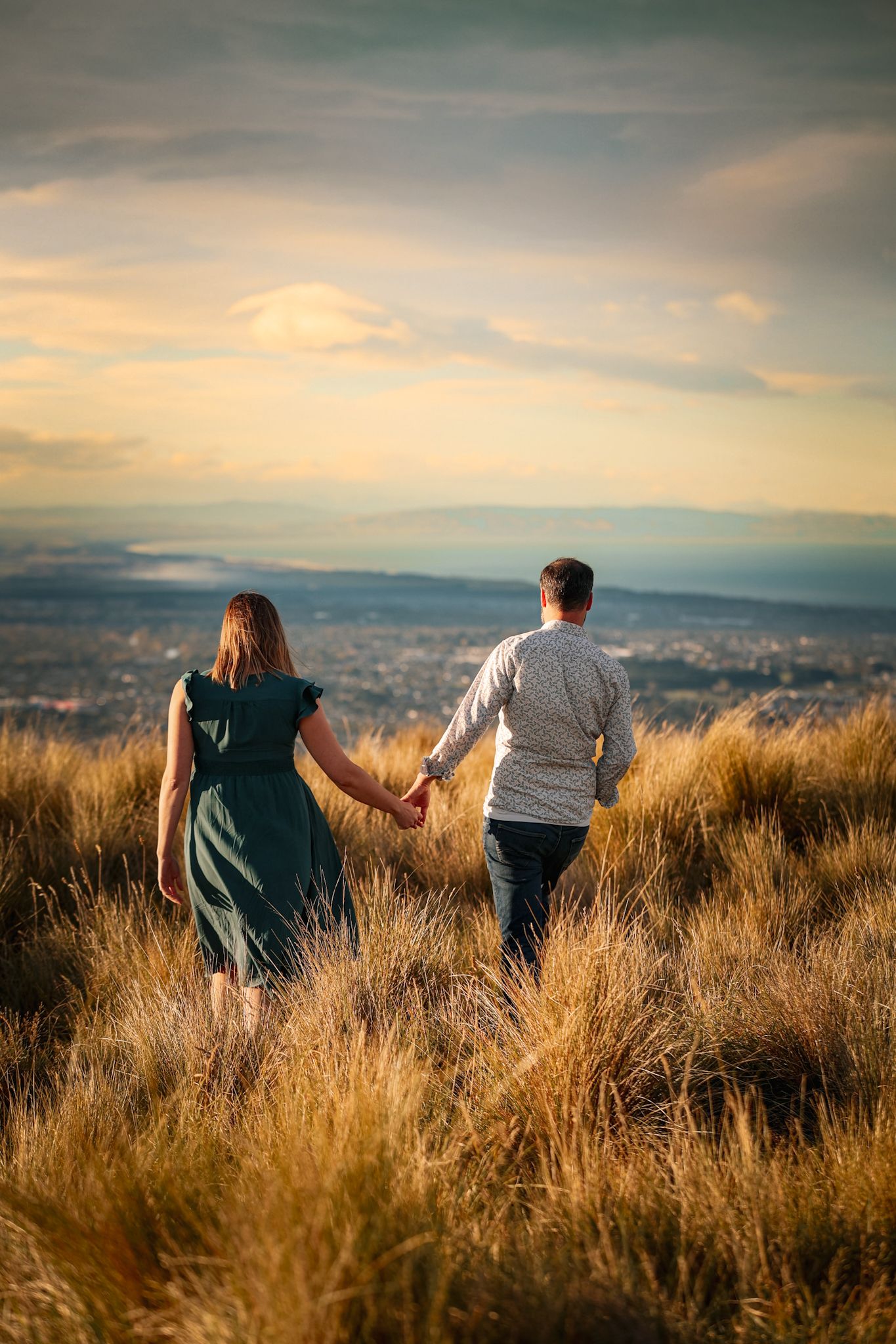Dreamy couple walking away from the camera at golden hour in the christchurch port hills