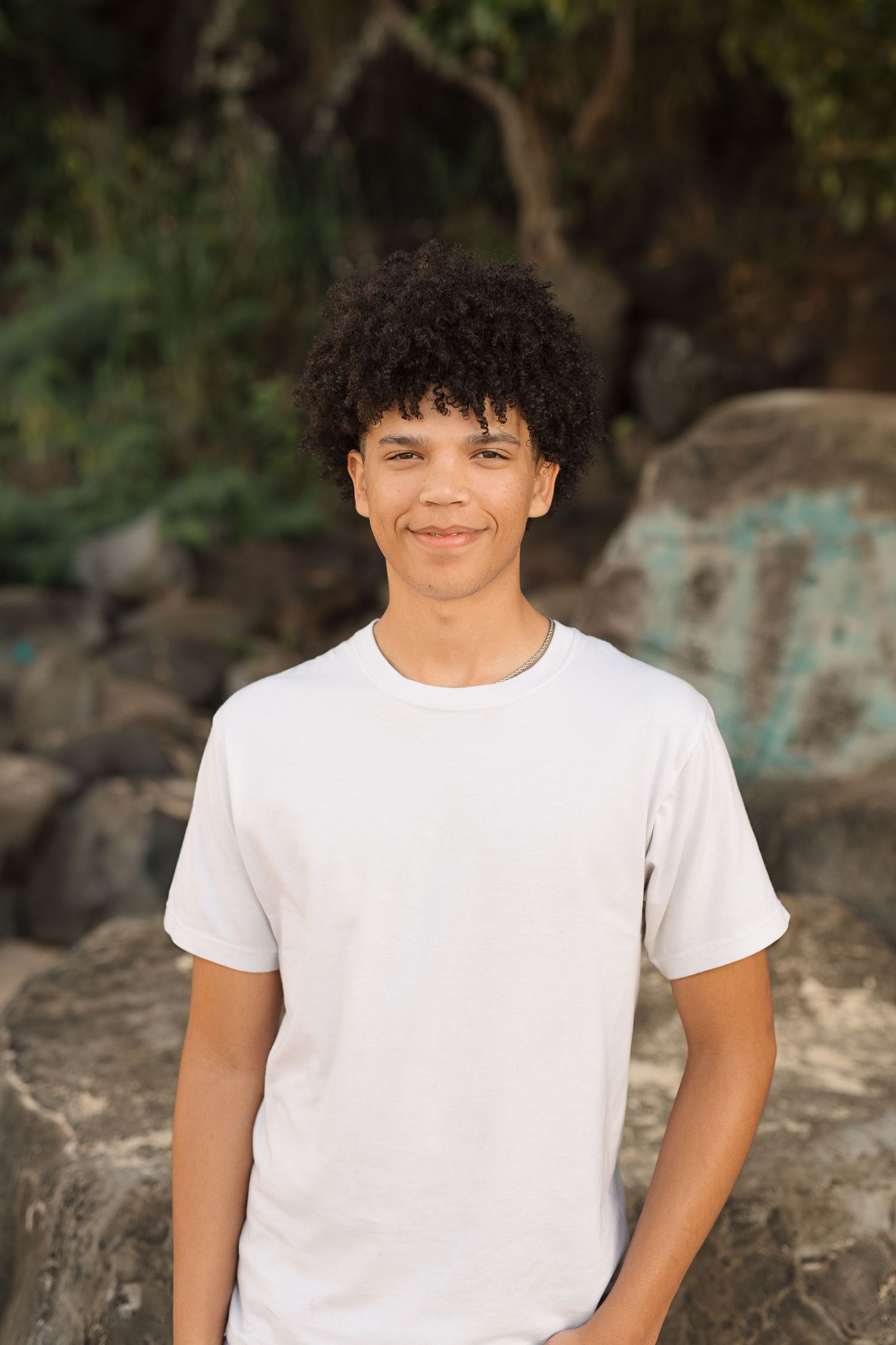 Candid portrait of person in white t-shirt against rocky coastal setting. waimea bay senior session north shore oahu hawaii