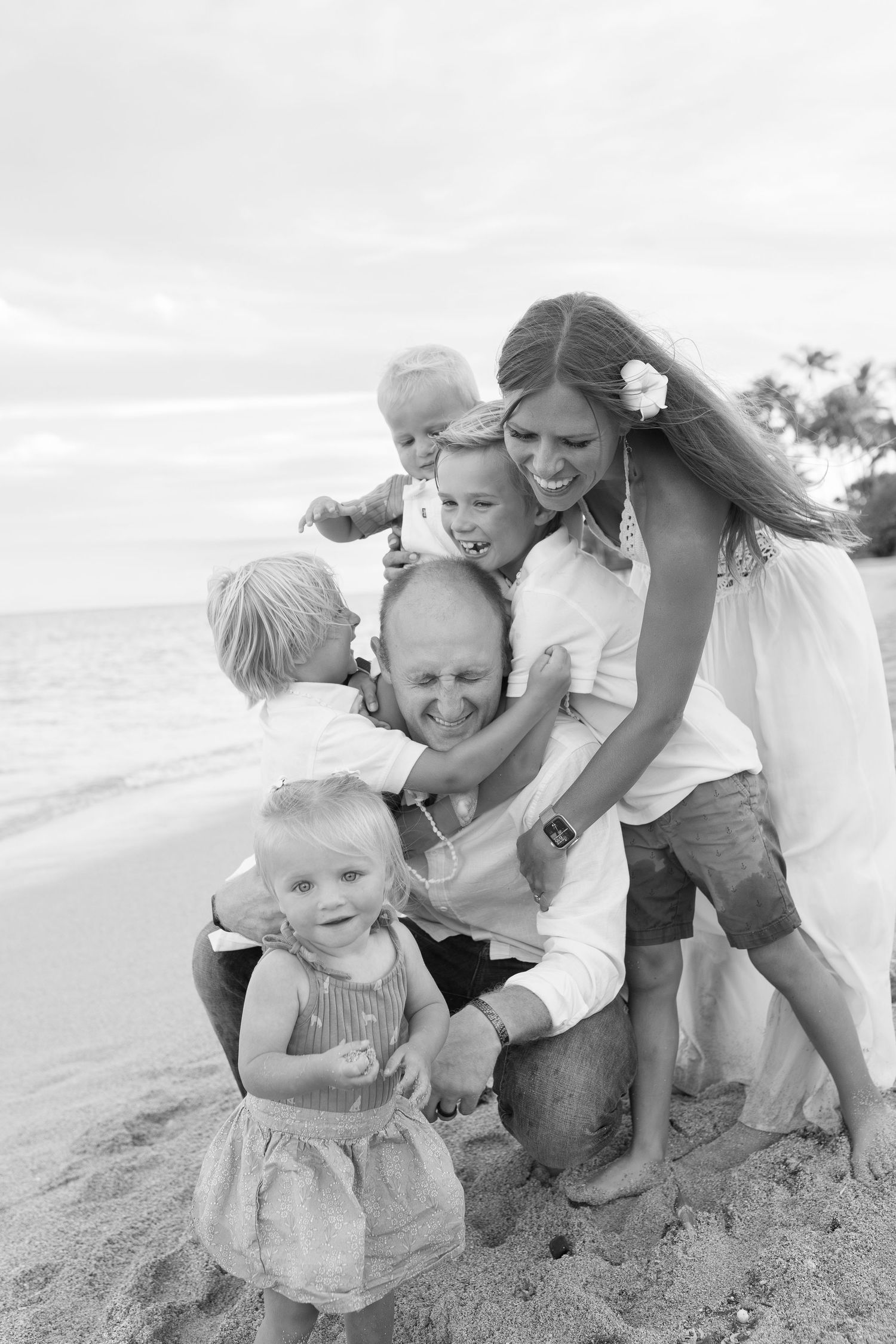 A family shares a joyful moment together on a beach in black and white photography.