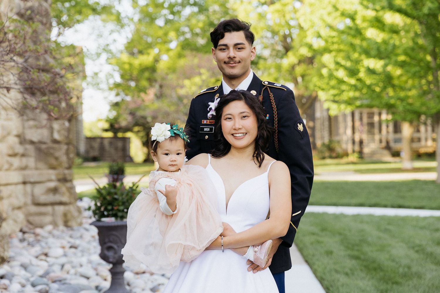 A family wedding portrait taken outdoors with greenery in background.