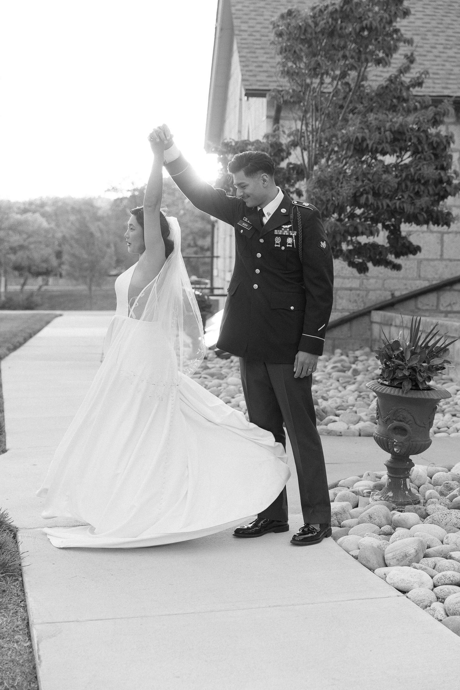 A black and white photo of a couple dancing in formal attire outside a church.