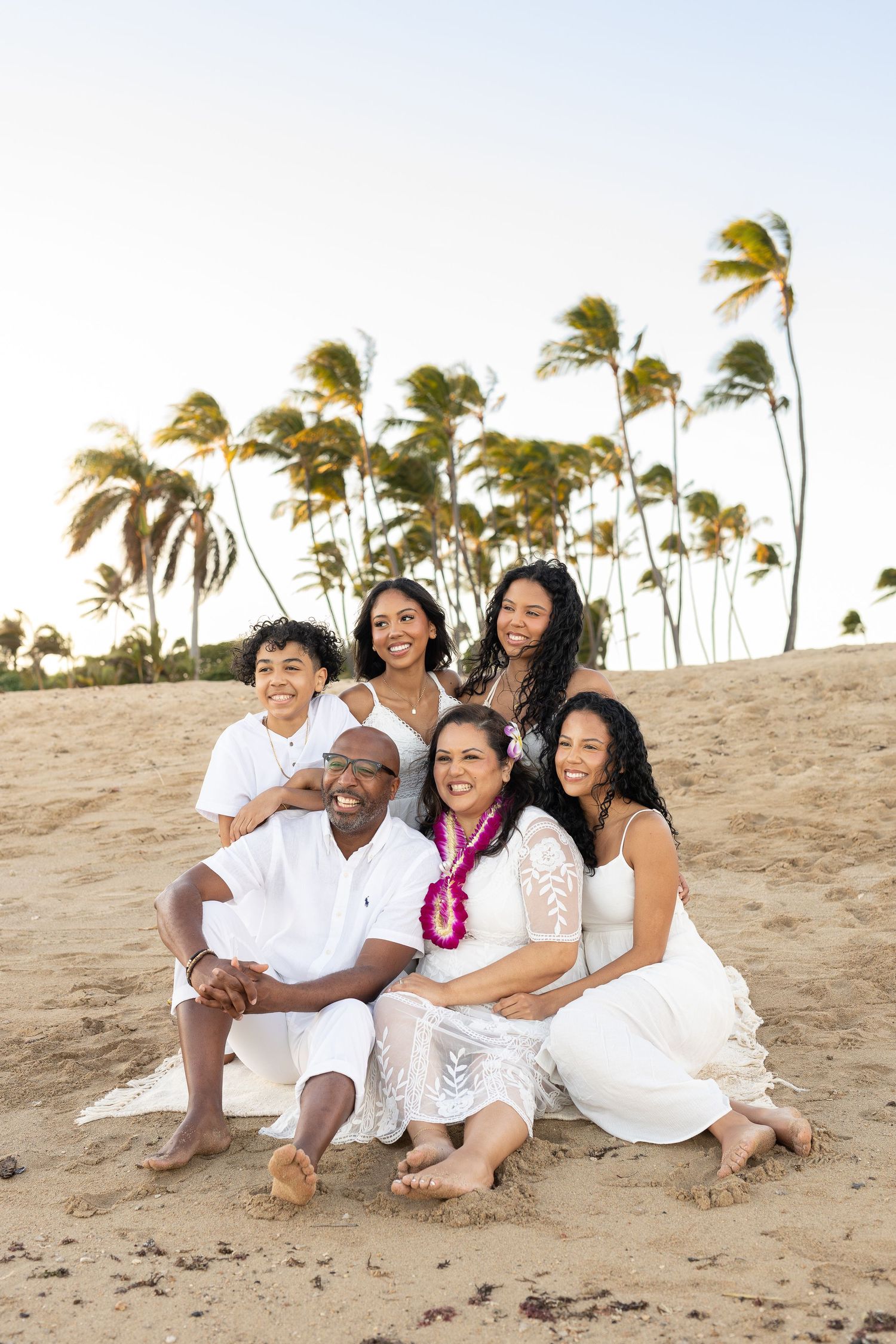 A beach family photoshoot with palm trees creating a tropical backdrop.