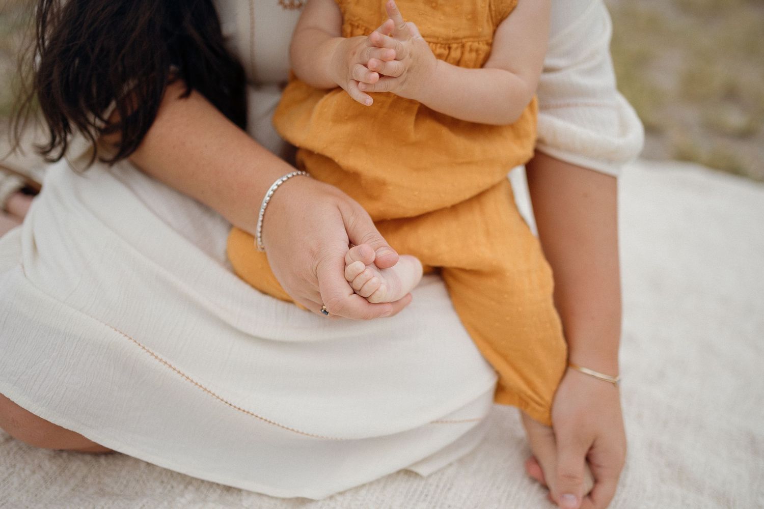 Close up view of hands resting on white dress fabric.