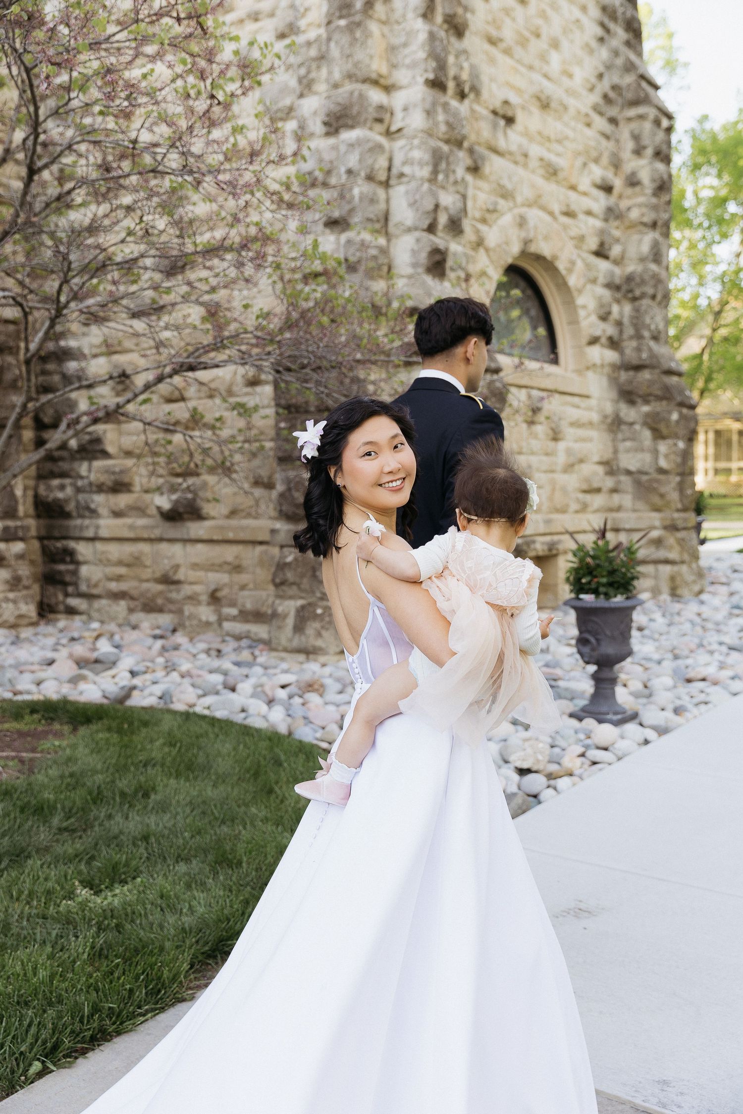 Elegant wedding scene outside historic stone church with delicate spring blossoms.
