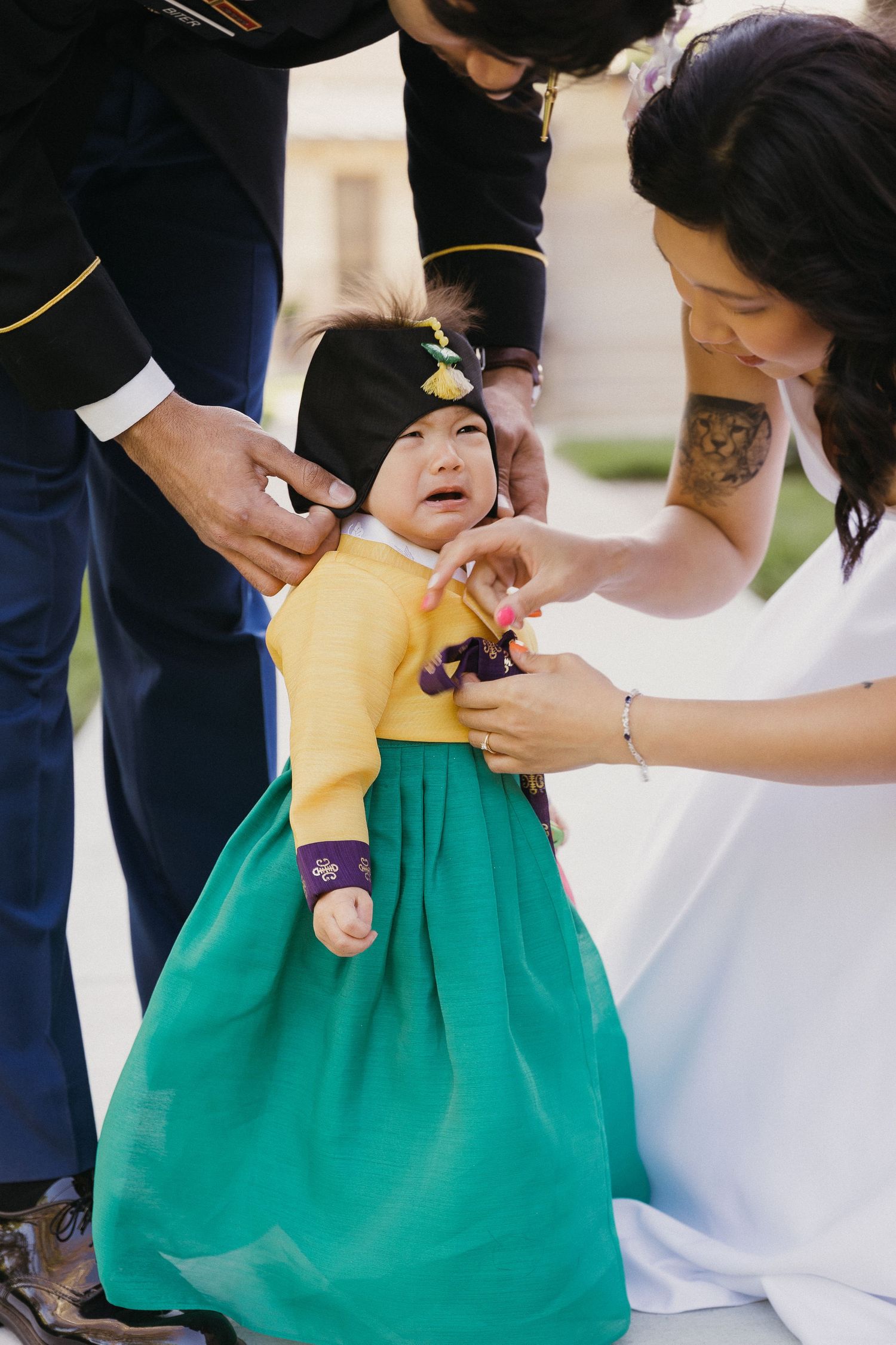 A tender family moment with a small child in a yellow and green dress.