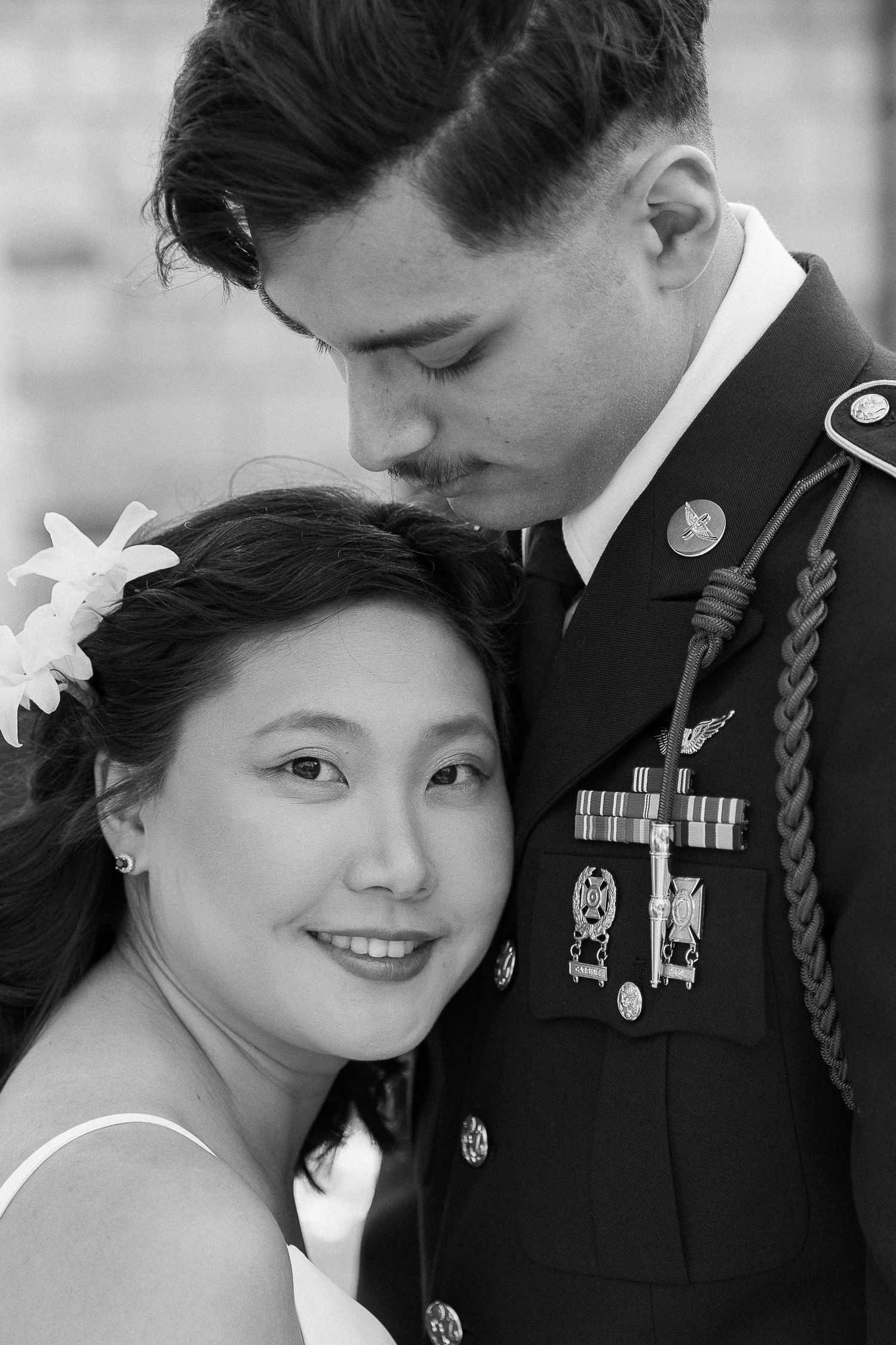 A tender black and white portrait of a military serviceman and bride sharing an intimate moment.