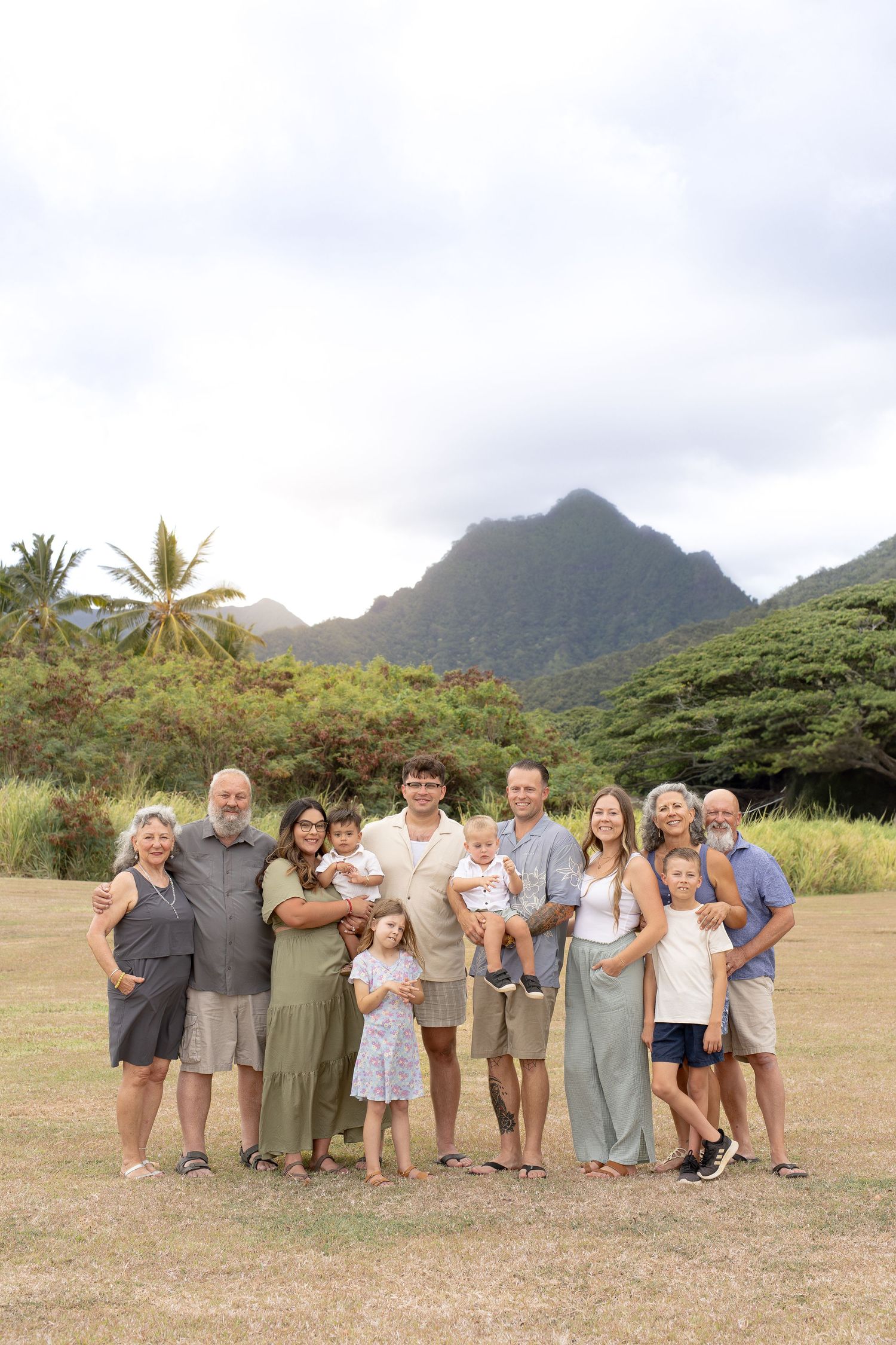 Group photo taken outdoors with scenic mountain backdrop and palm trees in Kauai, Hawaii.
