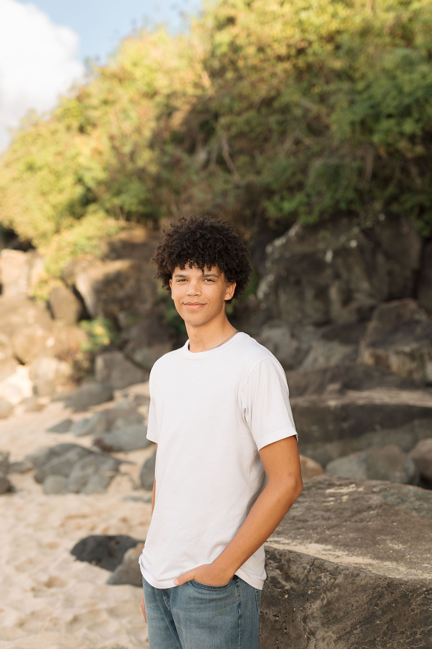 Natural outdoor portrait against rocky cliff backdrop wearing casual waimea bay senior session north shore oahu hawaii