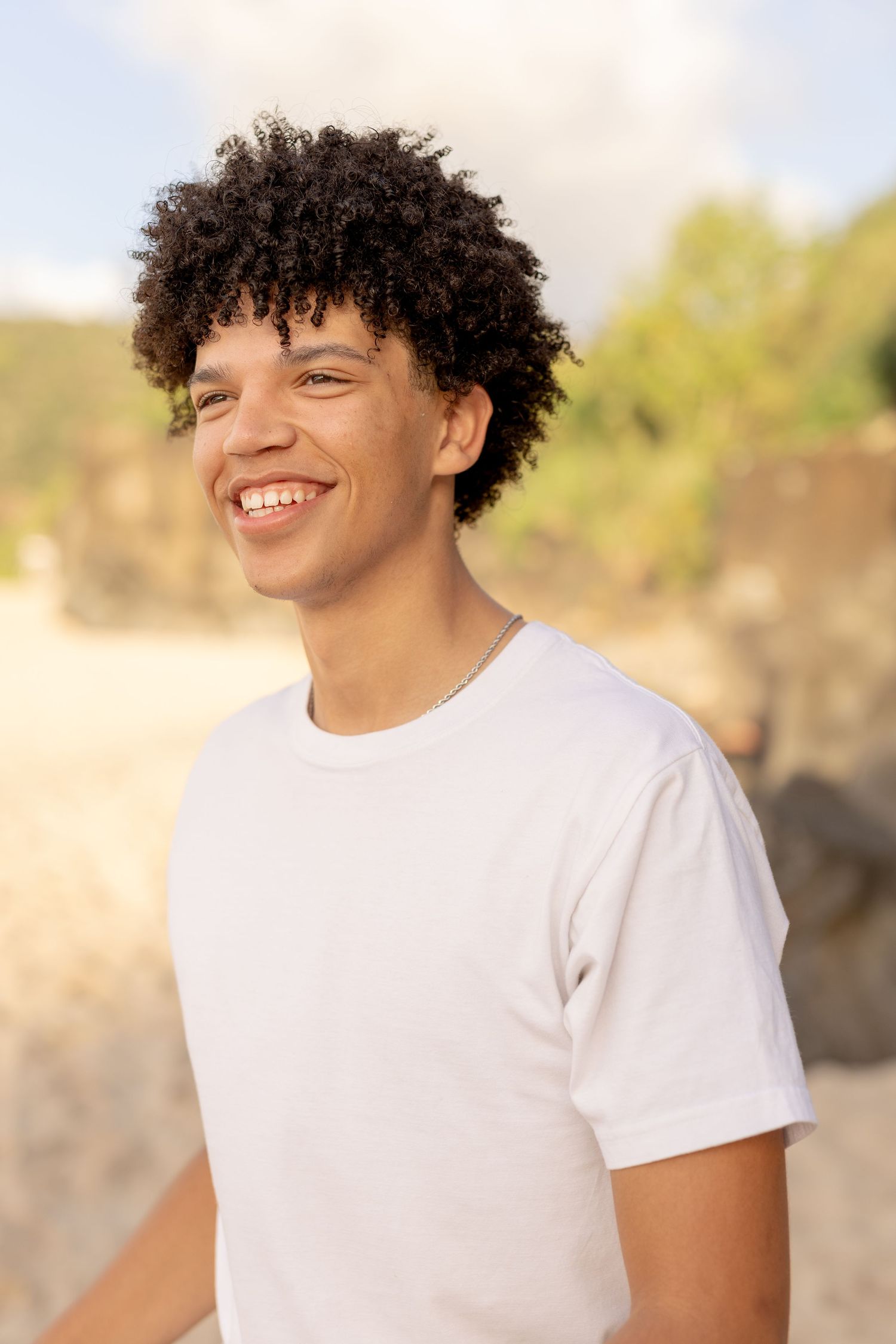 Close-up portrait of person in white t-shirt with joyful expression. waimea bay senior session north shore oahu hawaii