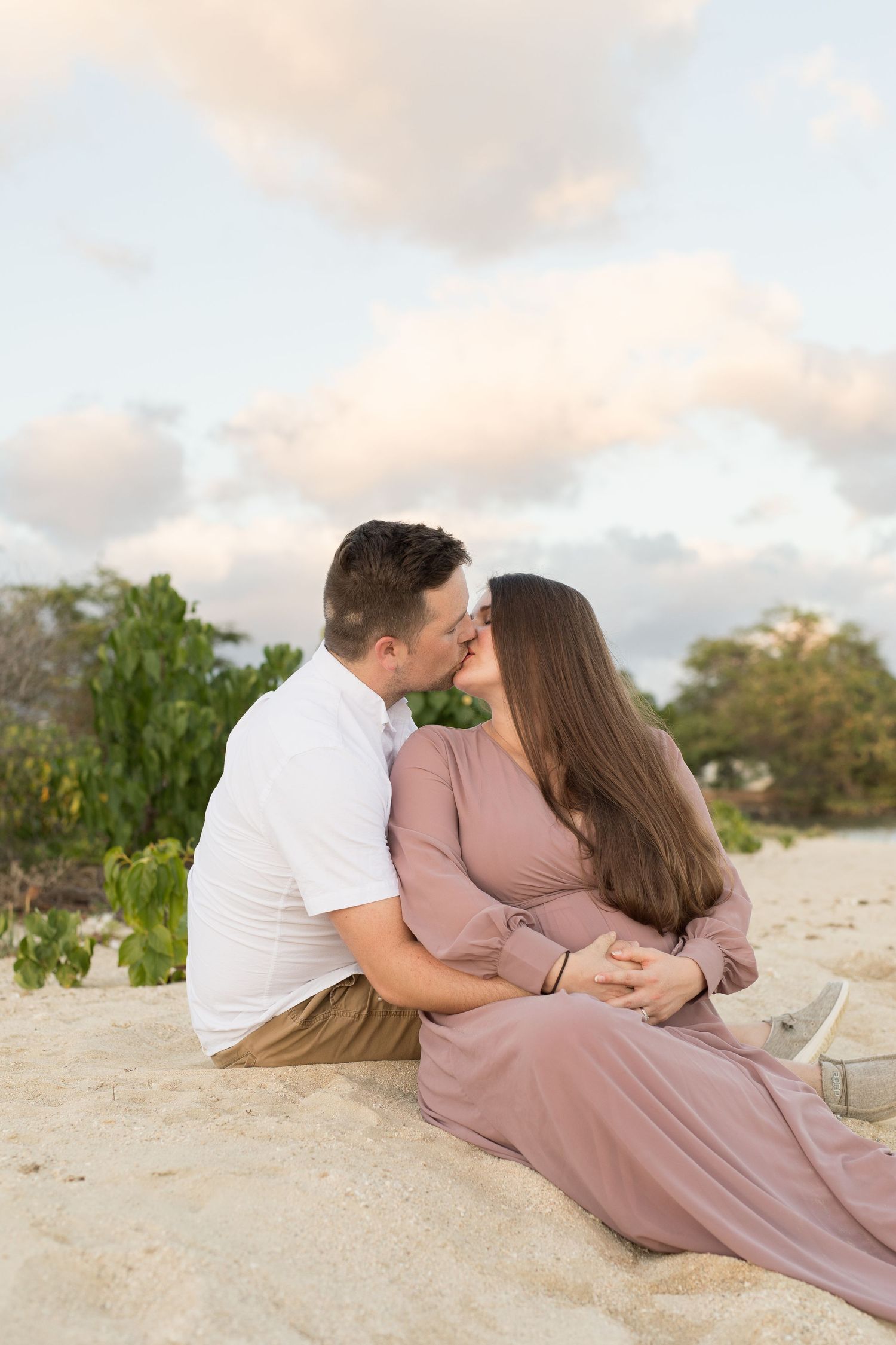 A romantic couple shares an intimate moment on the beach during sunset.
