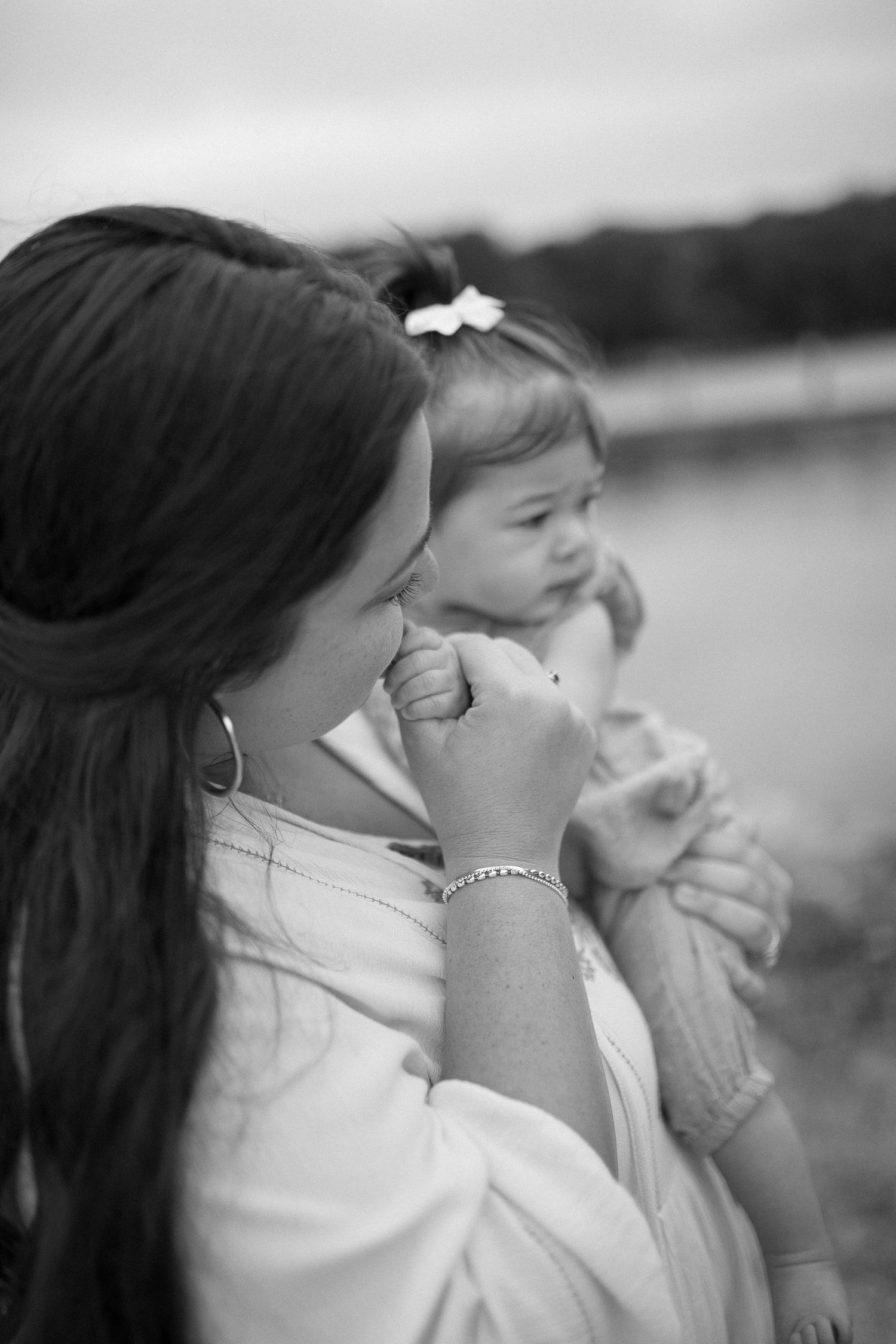 Intimate black and white portrait of mother and child by lake.