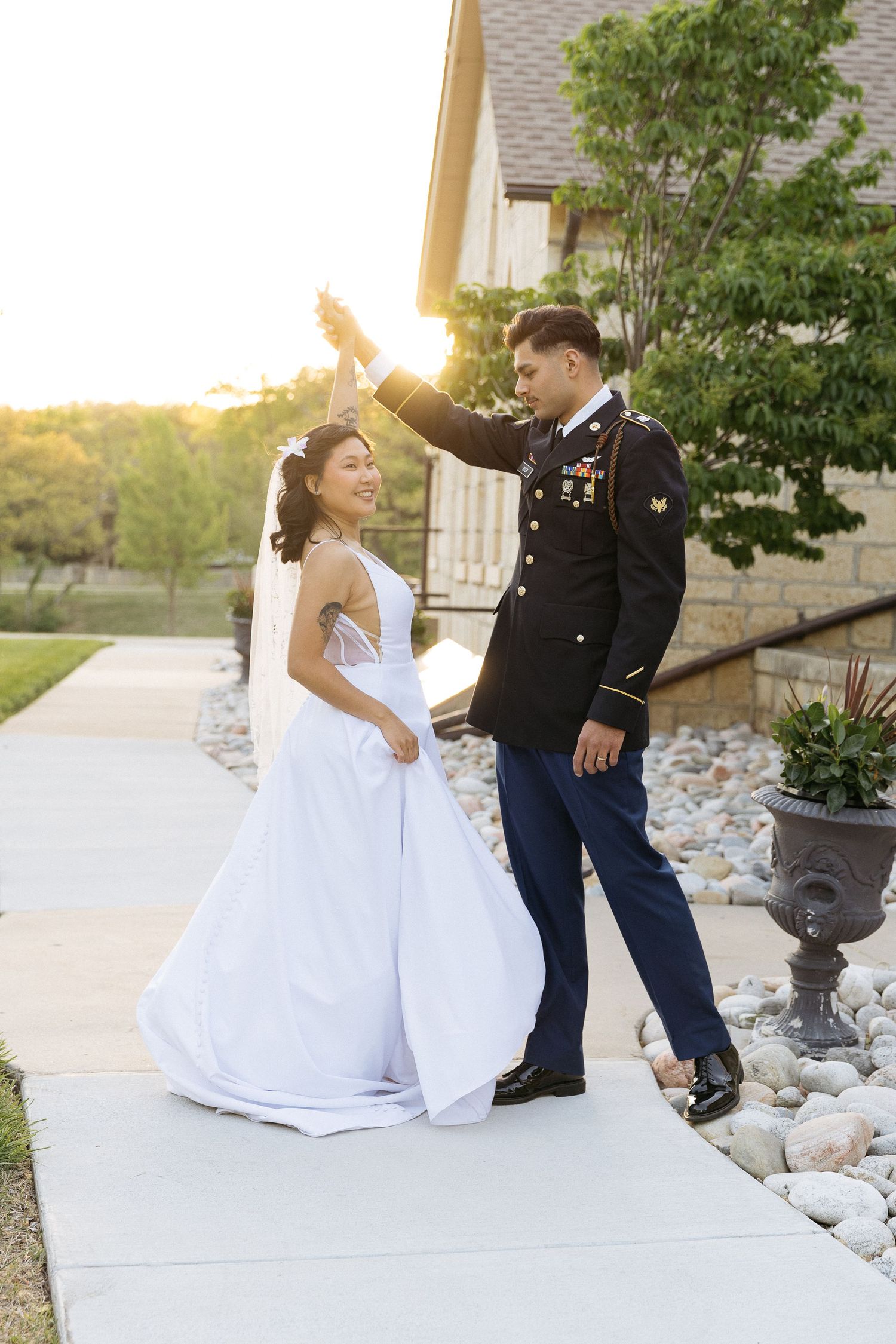 A sunset wedding photo with the couple dancing on a stone-lined path.