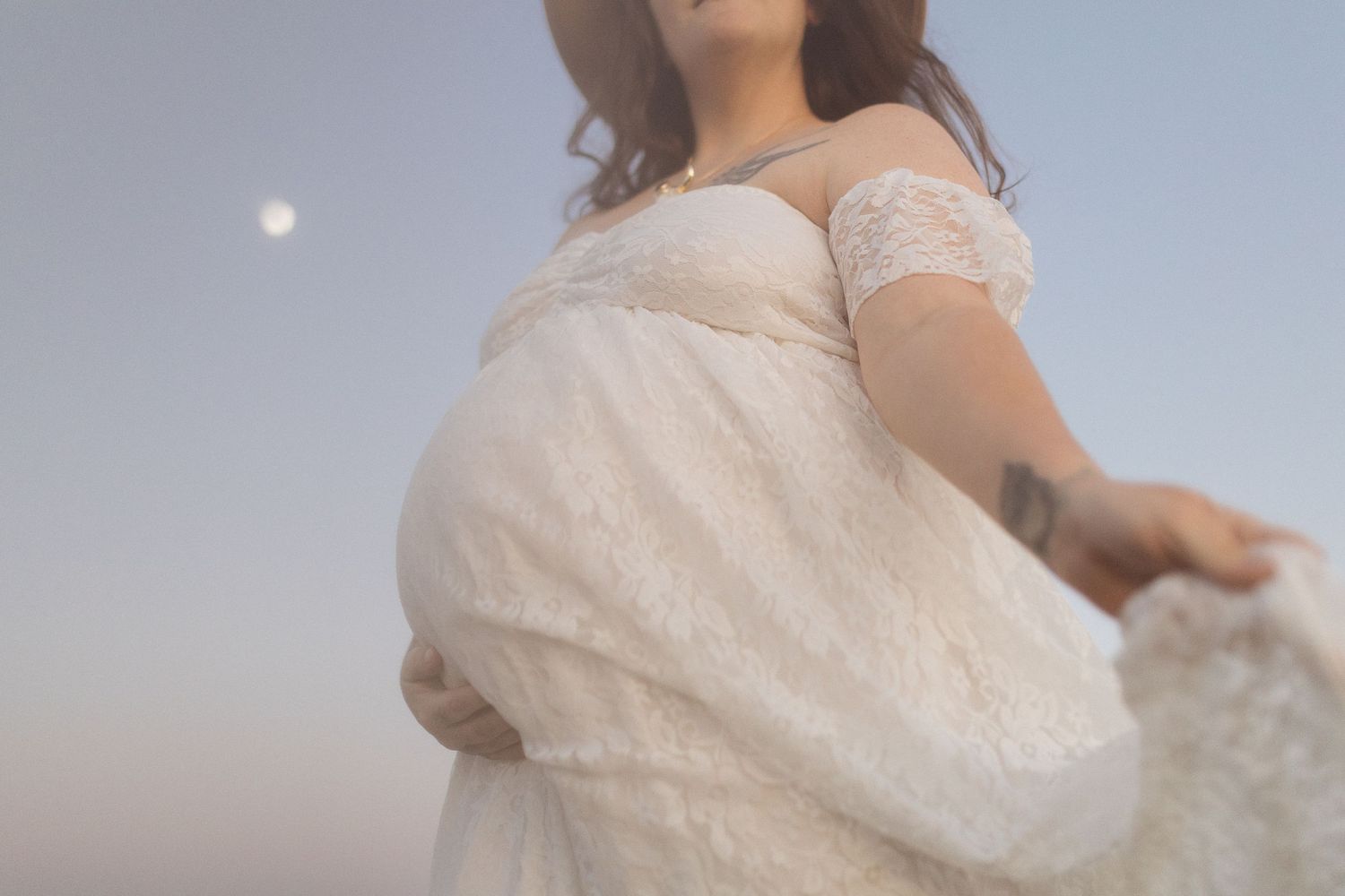 Low angle view of flowing white maternity dress against twilight sky.
