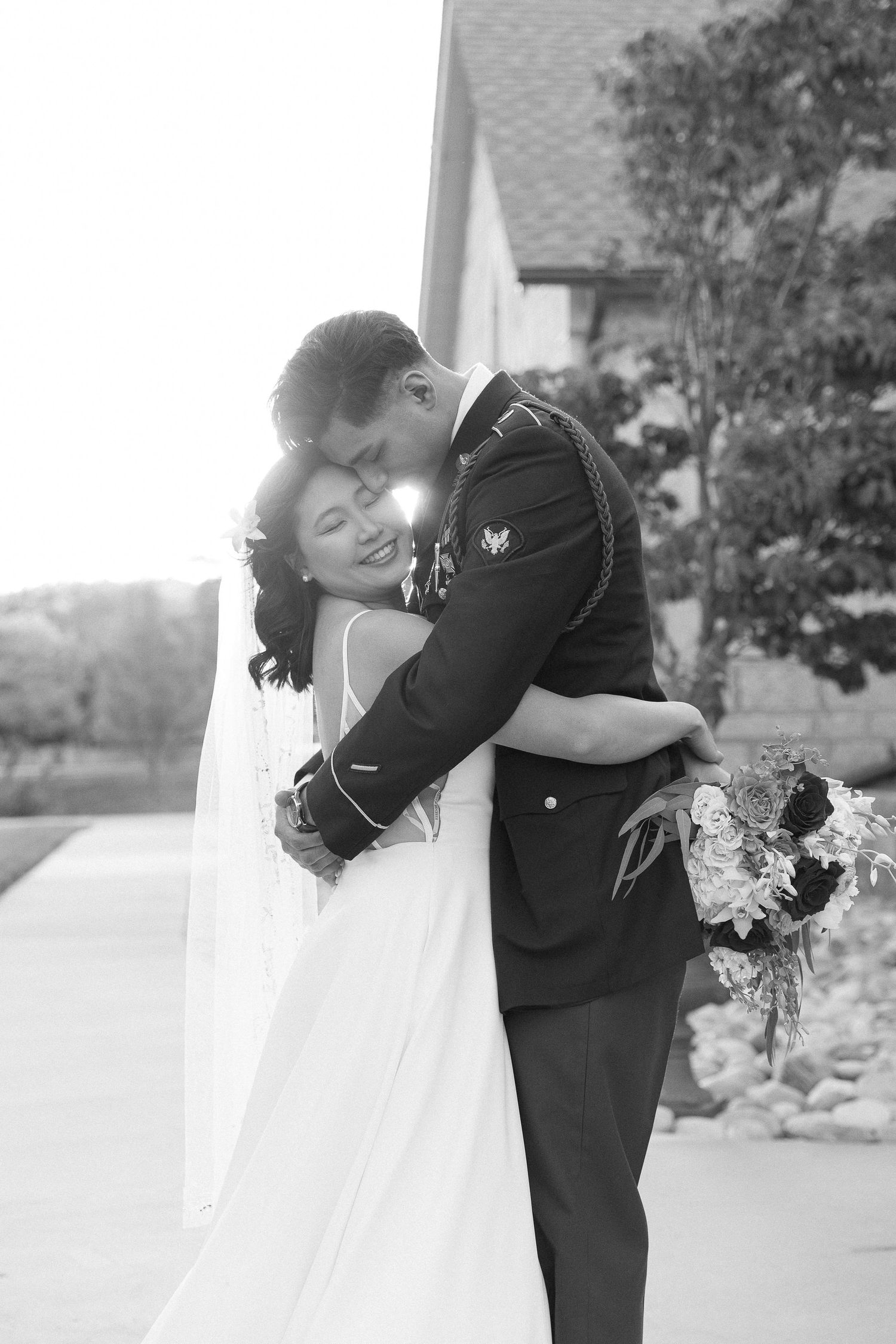 A romantic black and white portrait of a wedding couple sharing an intimate embrace.