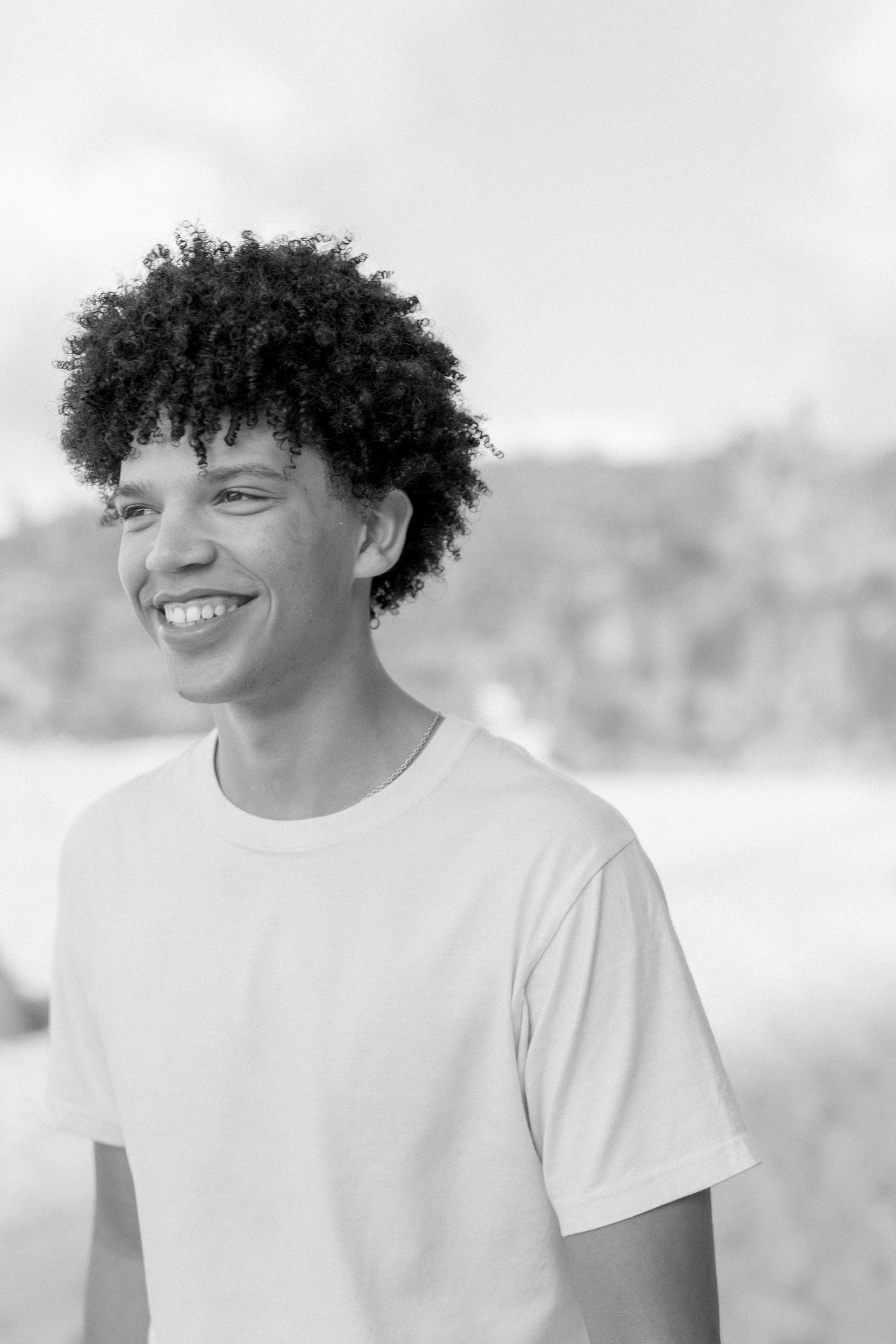 Black and white portrait showing genuine smile against beach background. waimea bay senior session north shore oahu hawaii