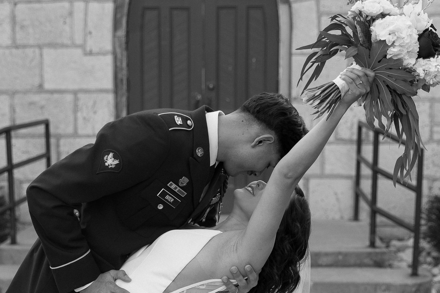 A dramatic black and white wedding photo showing a romantic dip pose.