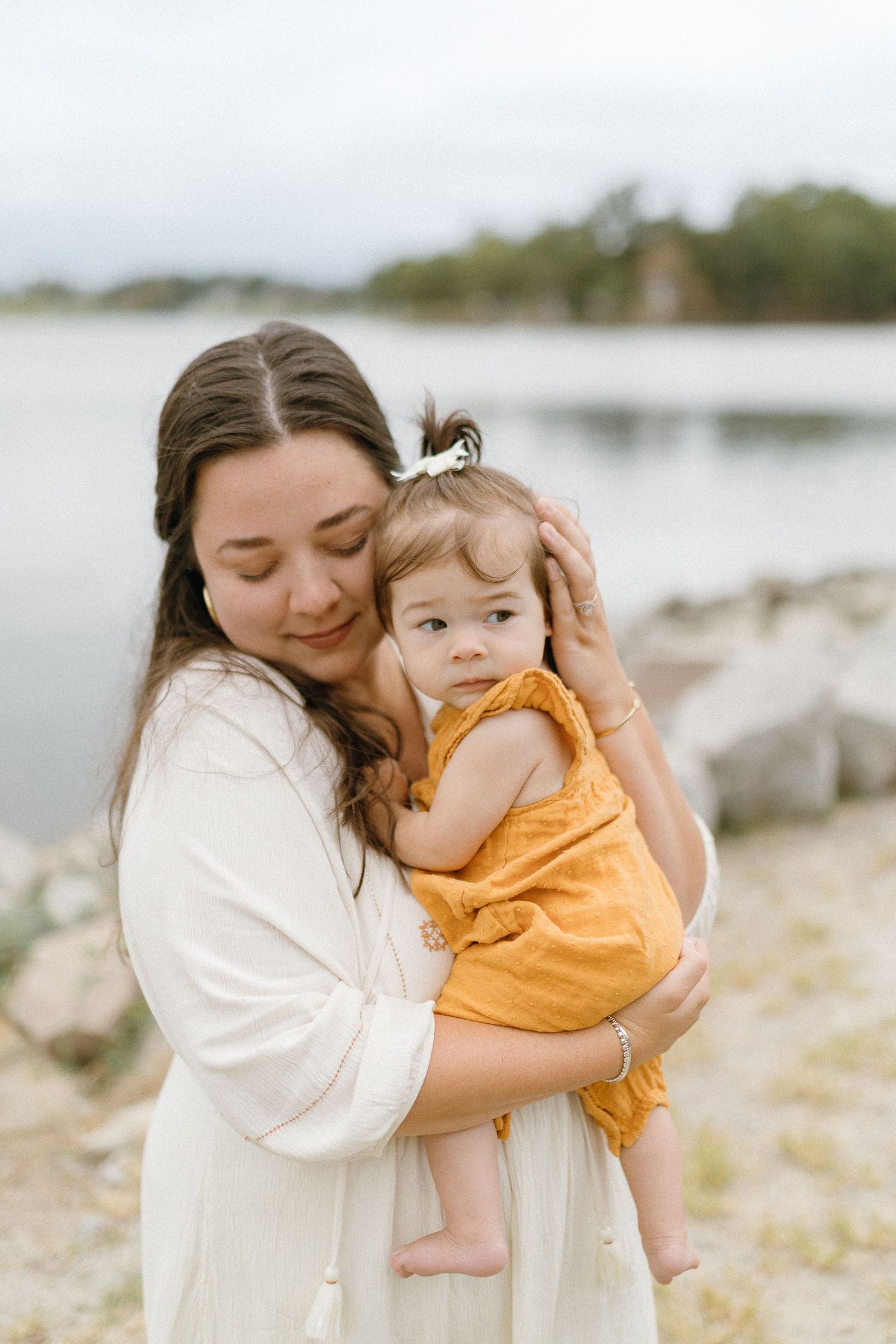 Tender moment captured between parent and child against serene lake backdrop.