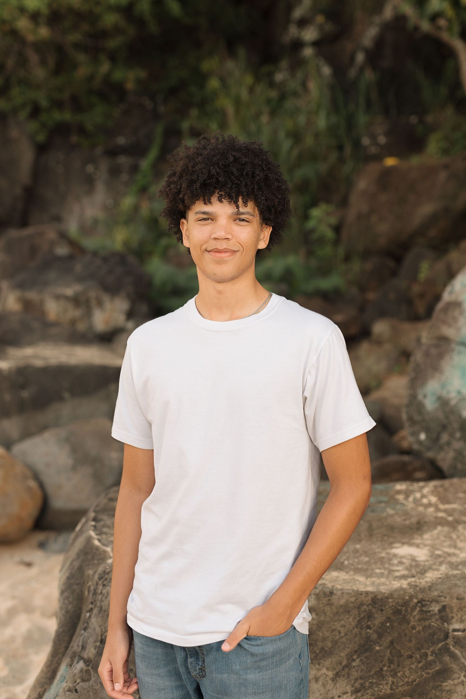 Casual portrait of person in white t-shirt against rocky beach background. waimea bay oahu hawaii