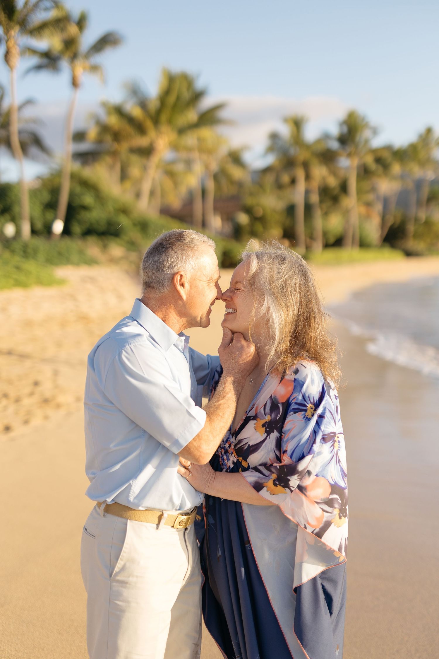 A happy couple shares a romantic moment together on a tropical beach with palm trees at sunset.