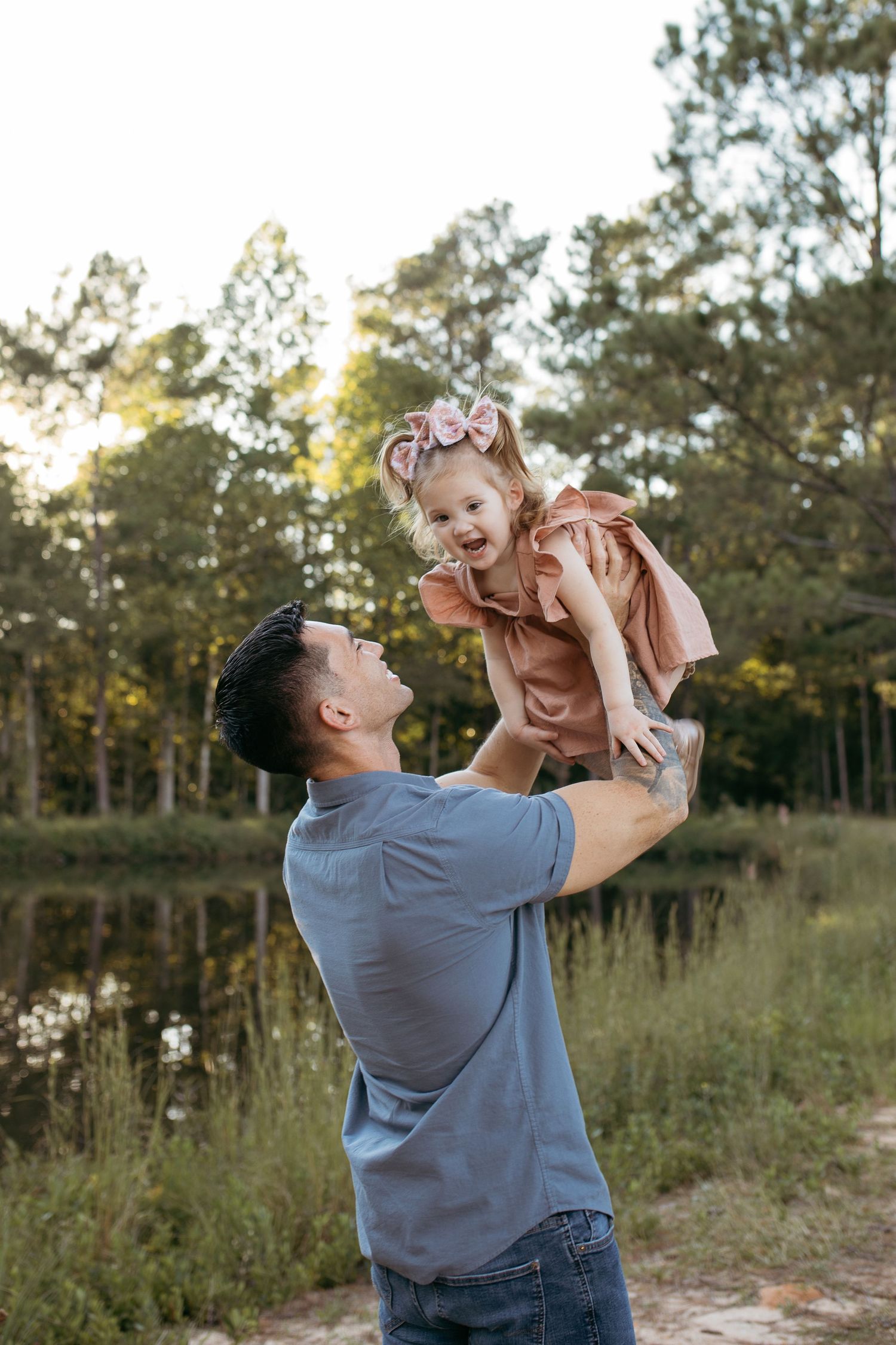 A touching moment between parent and child playing by a lake at sunset.