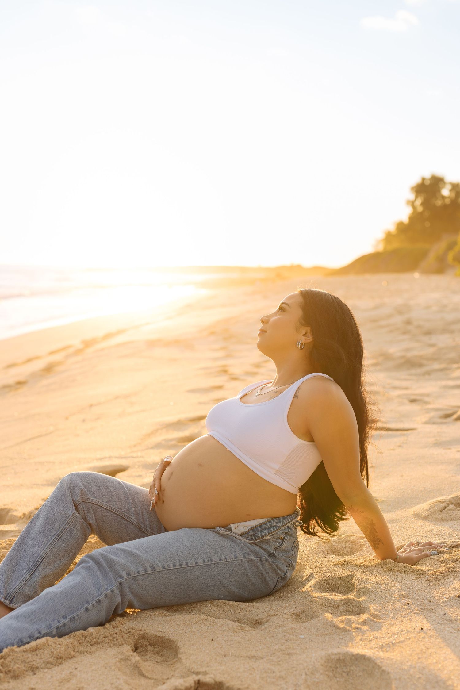 A relaxed beach maternity photo with golden hour lighting.
