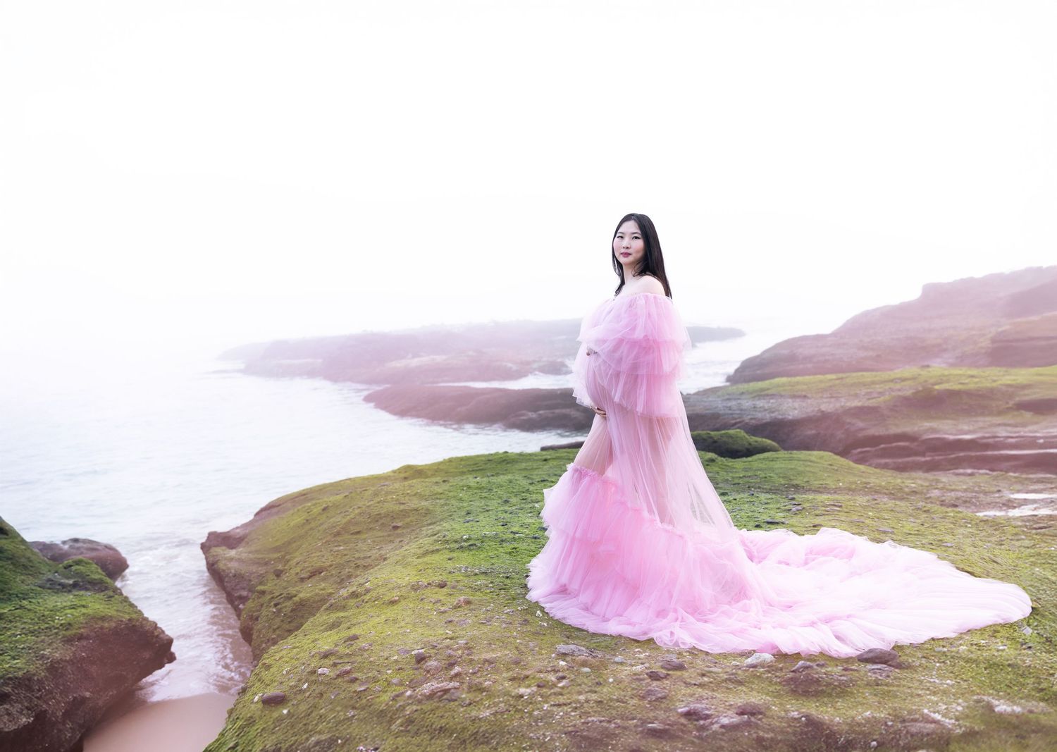 A beautiful and elegant maternity photoshoot at the beach, with soft lighting and the ocean as a stunning backdrop.