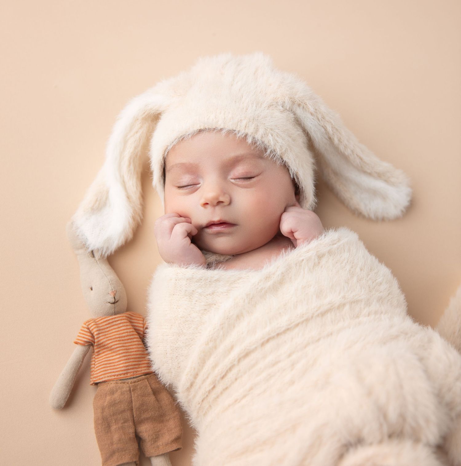 A baby boy peacefully sleeps in an Easter bunny outfit during his milestone photo session.