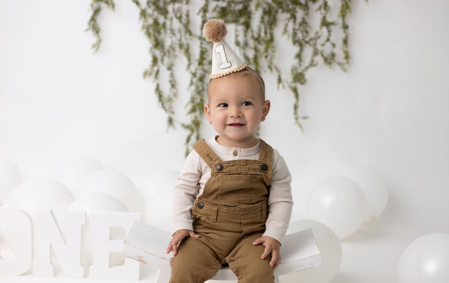 A one-year-old baby sits in a timeless, minimalistic first birthday setup, featuring soft tones and elegant simplicity.