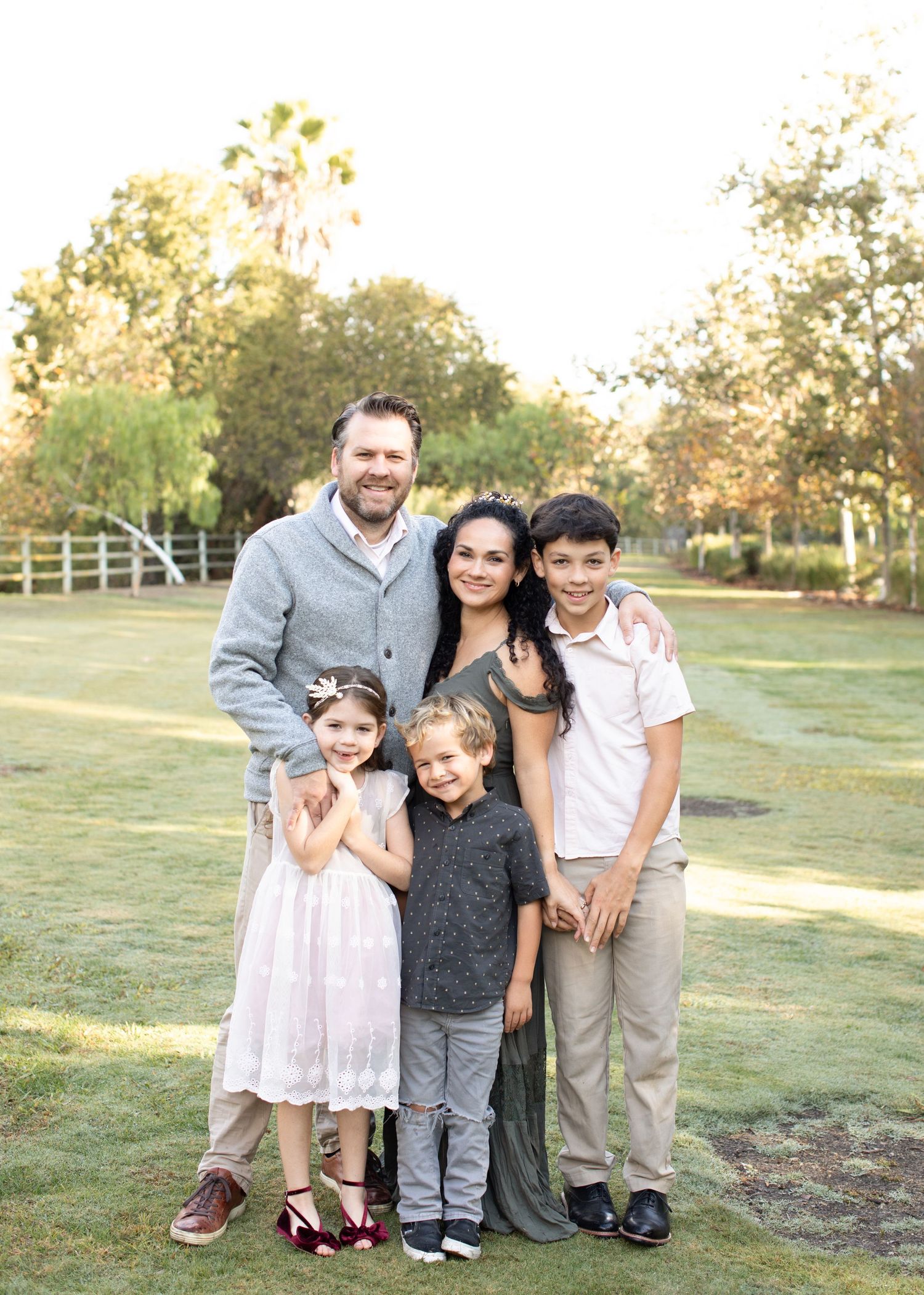 A family poses together during their outdoor session, capturing a joyful and loving moment in a natural setting.