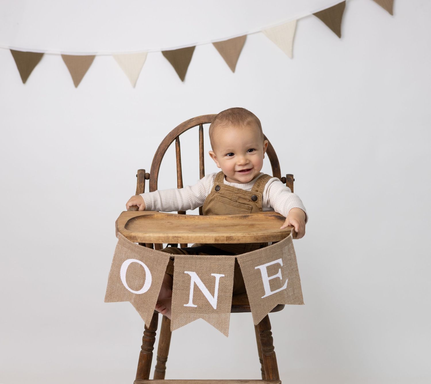 A baby sits on a vintage high chair, capturing a classic and timeless moment during their photo session.