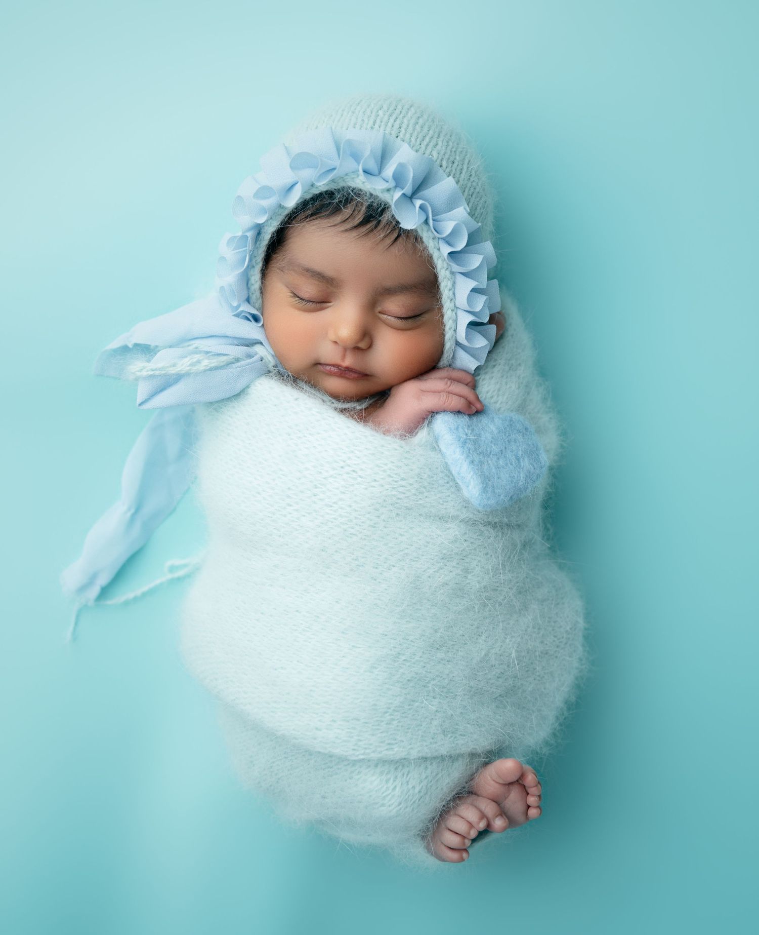 A newborn baby peacefully sleeps during a studio photoshoot in Orange County, CA, with soft lighting and serene props.