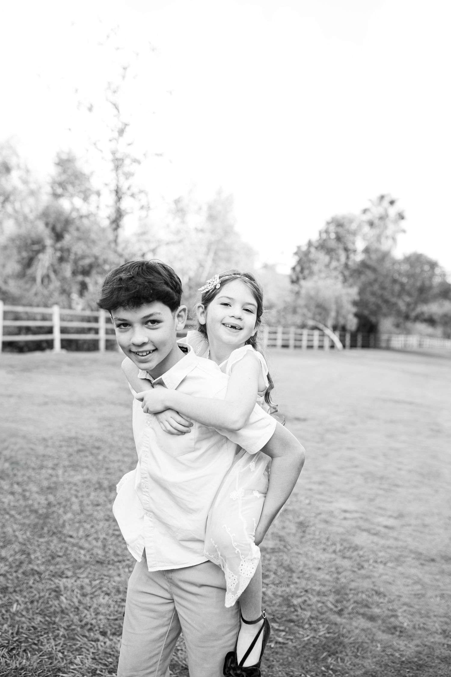 A brother gives his sister a piggyback ride during a fun family outdoor photo session.