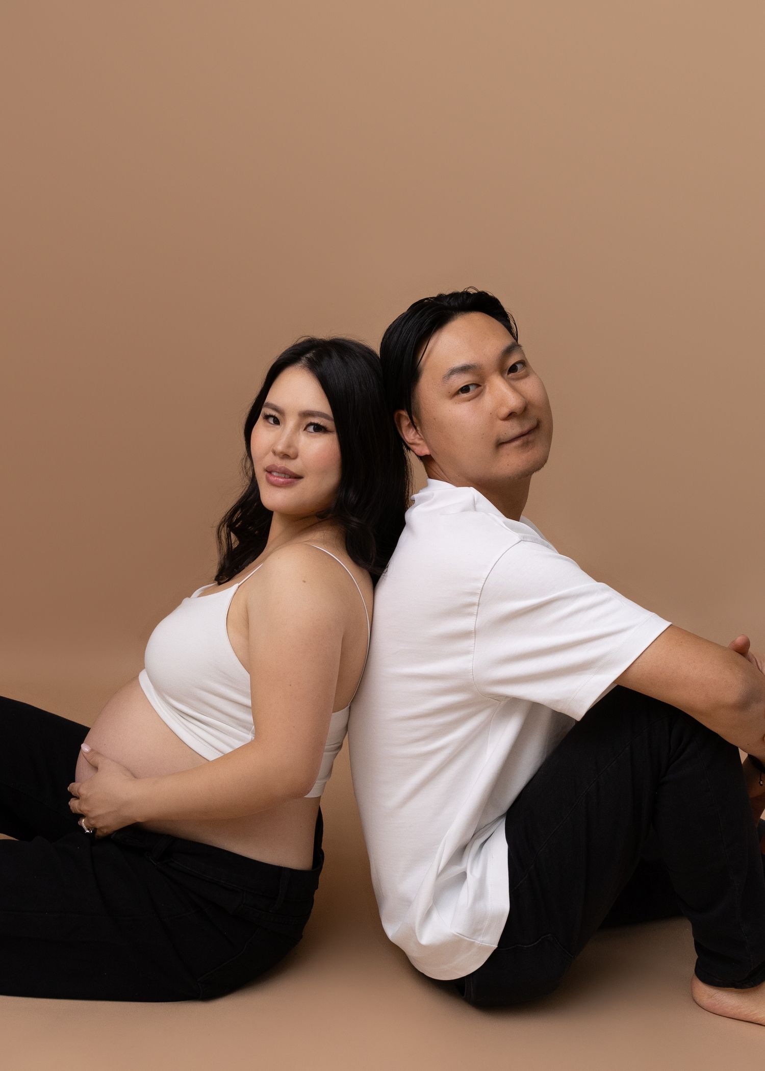 A pregnant woman poses with her partner in the studio during their maternity session.