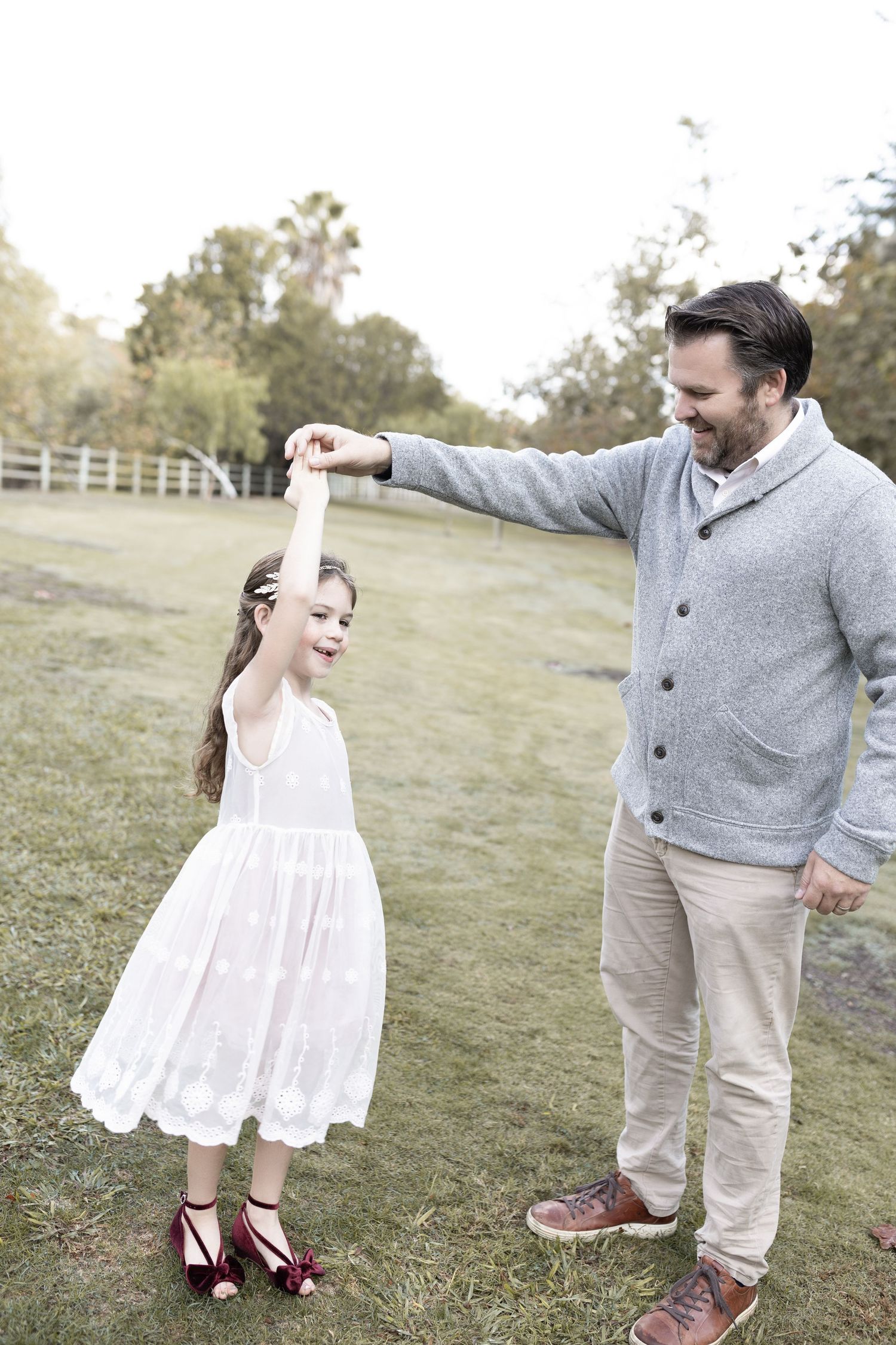 A young girl dances with her dad, sharing a joyful and loving moment.