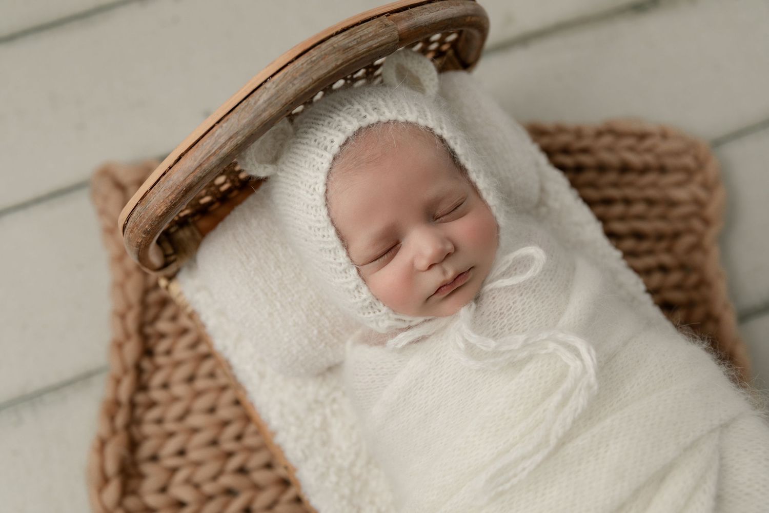 A baby boy sleeps peacefully during his in-home newborn session in Yorba Linda, CA, surrounded by soft, cozy props.