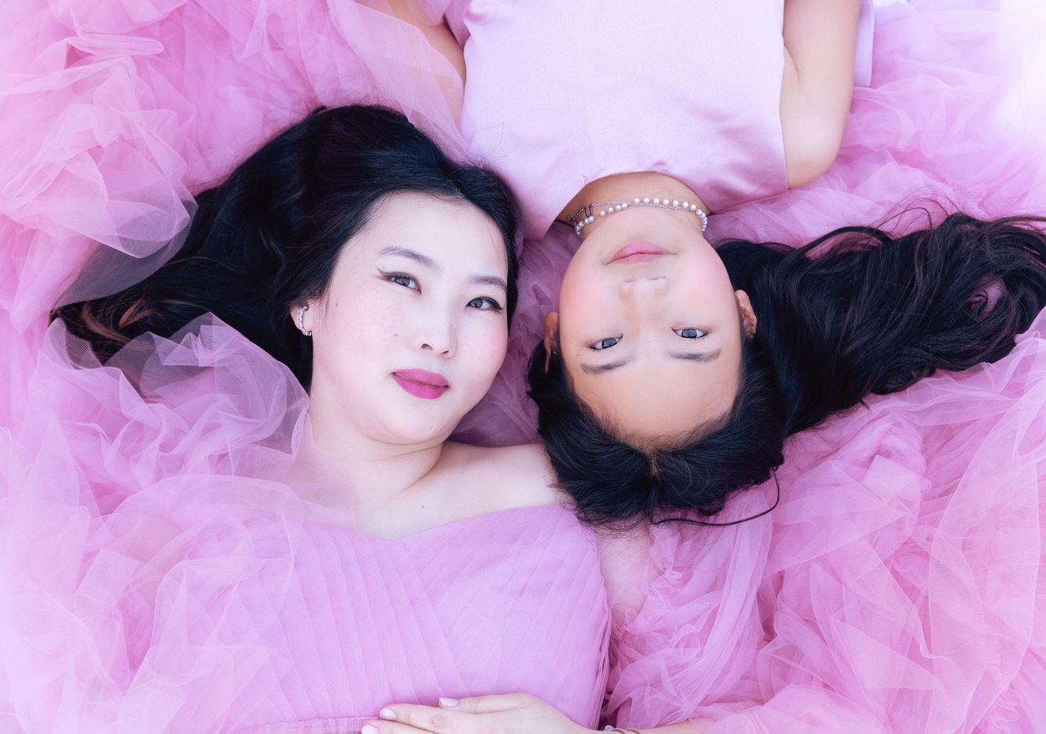 A mother poses with her daughter during an outdoor maternity photoshoot, capturing a tender and joyful moment.