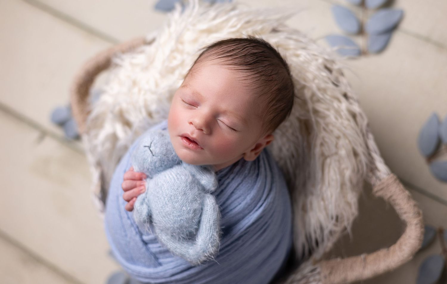 A newborn baby boy is swaddled in a basket during his photo session in my Santa Ana studio, creating a peaceful and cozy moment.
