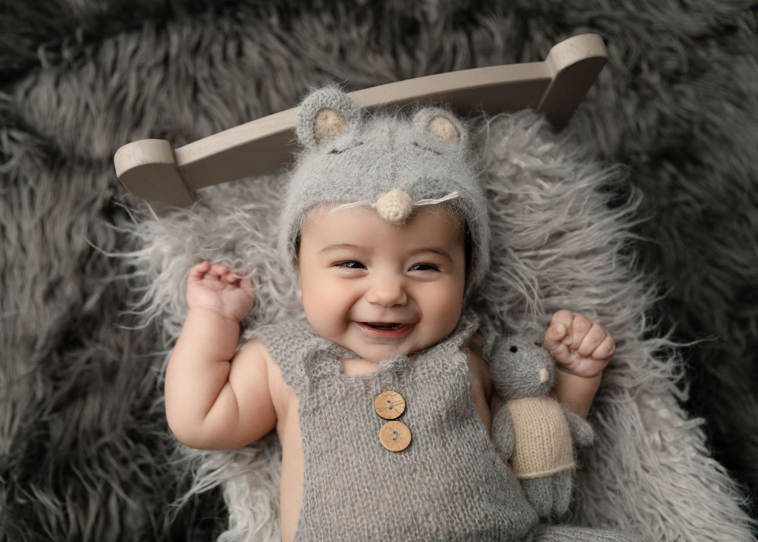 A baby boy smiles in a cute mouse-themed outfit during his milestone session.