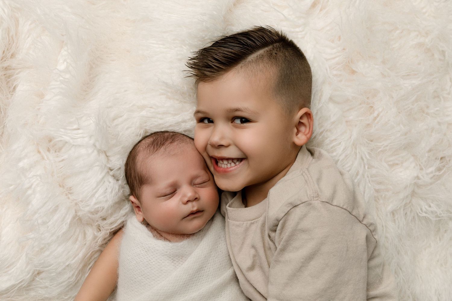 Siblings pose together during an in-home newborn session in Orange County, CA, capturing a sweet and loving moment.