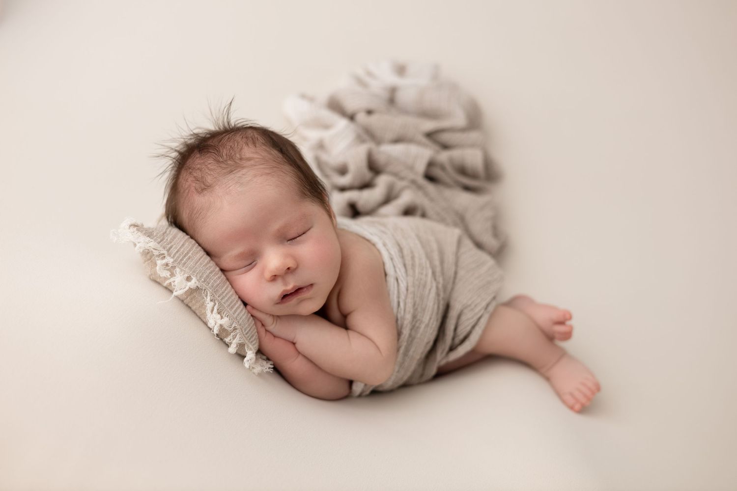 A newborn baby boy peacefully sleeps on his side, swaddled in a soft blanket, with gentle lighting highlighting his delicate features.
