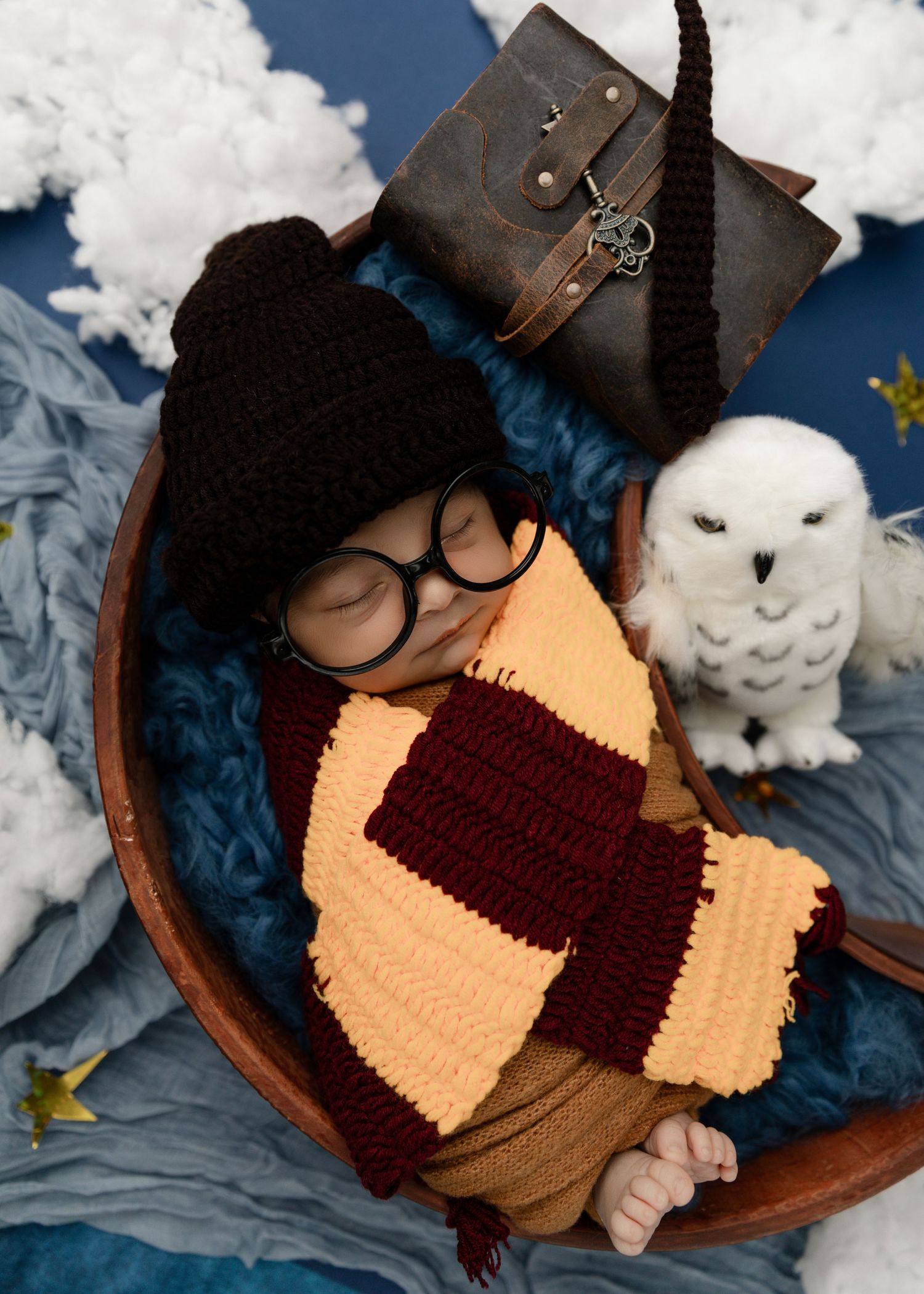 A newborn baby boy in a Harry Potter-themed outfit sleeps peacefully on a themed backdrop.
