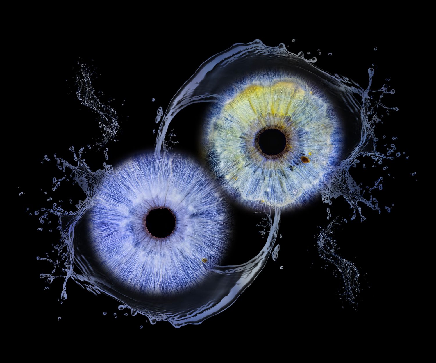 Two glowing eyes with blue and yellow irises surrounded by water splashes on a black background.