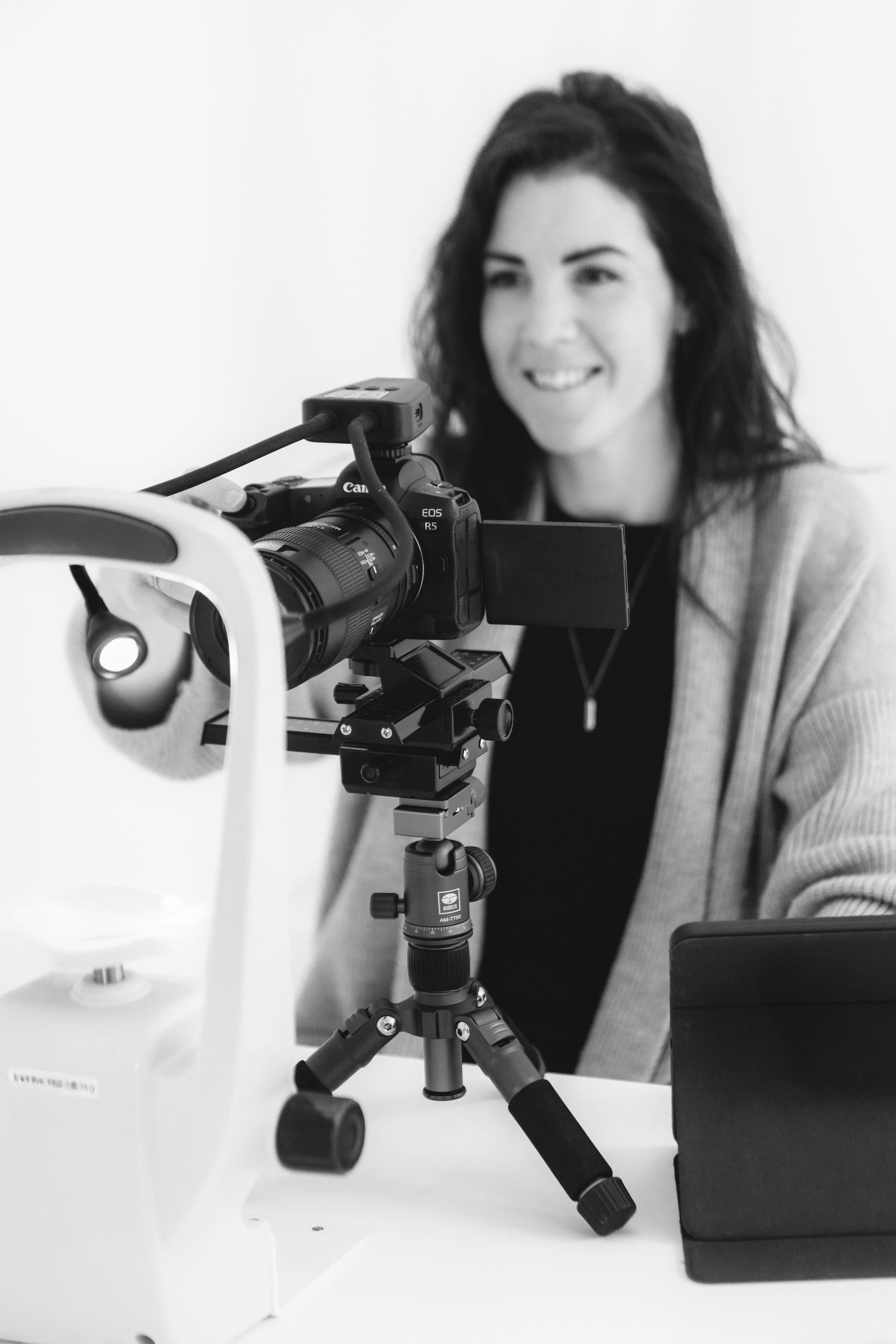 Professional photographer with a camera mounted on a tripod in a studio setting.