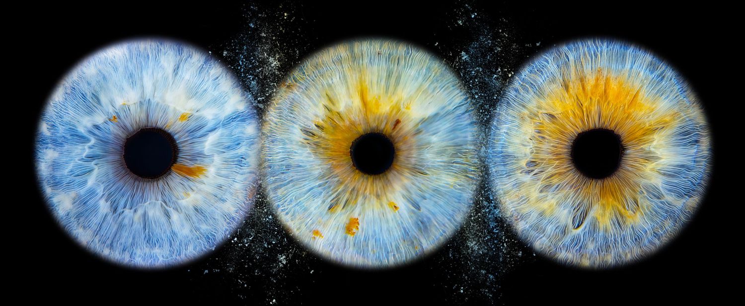 Three human eyes with blue and gold irises displayed side by side against a dark starry background.