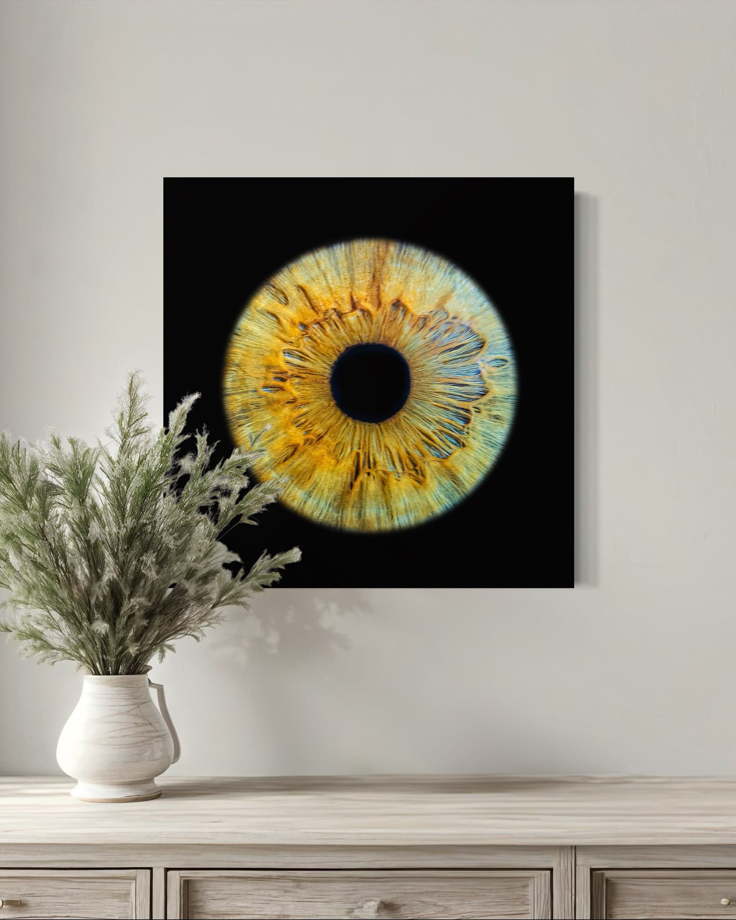 Striking wall art featuring a detailed yellow and turquoise iris eye on black background with dried flowers in white vase.